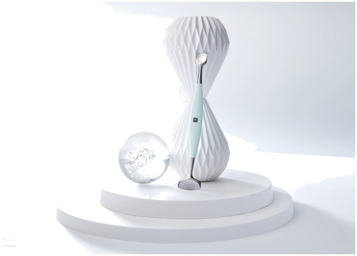 Silberfarbenes Facial Pore Refiner Tool aus Edelstahl mit zwei funktionalen Enden für die Gesichtspflege, liegend fotografiert.
