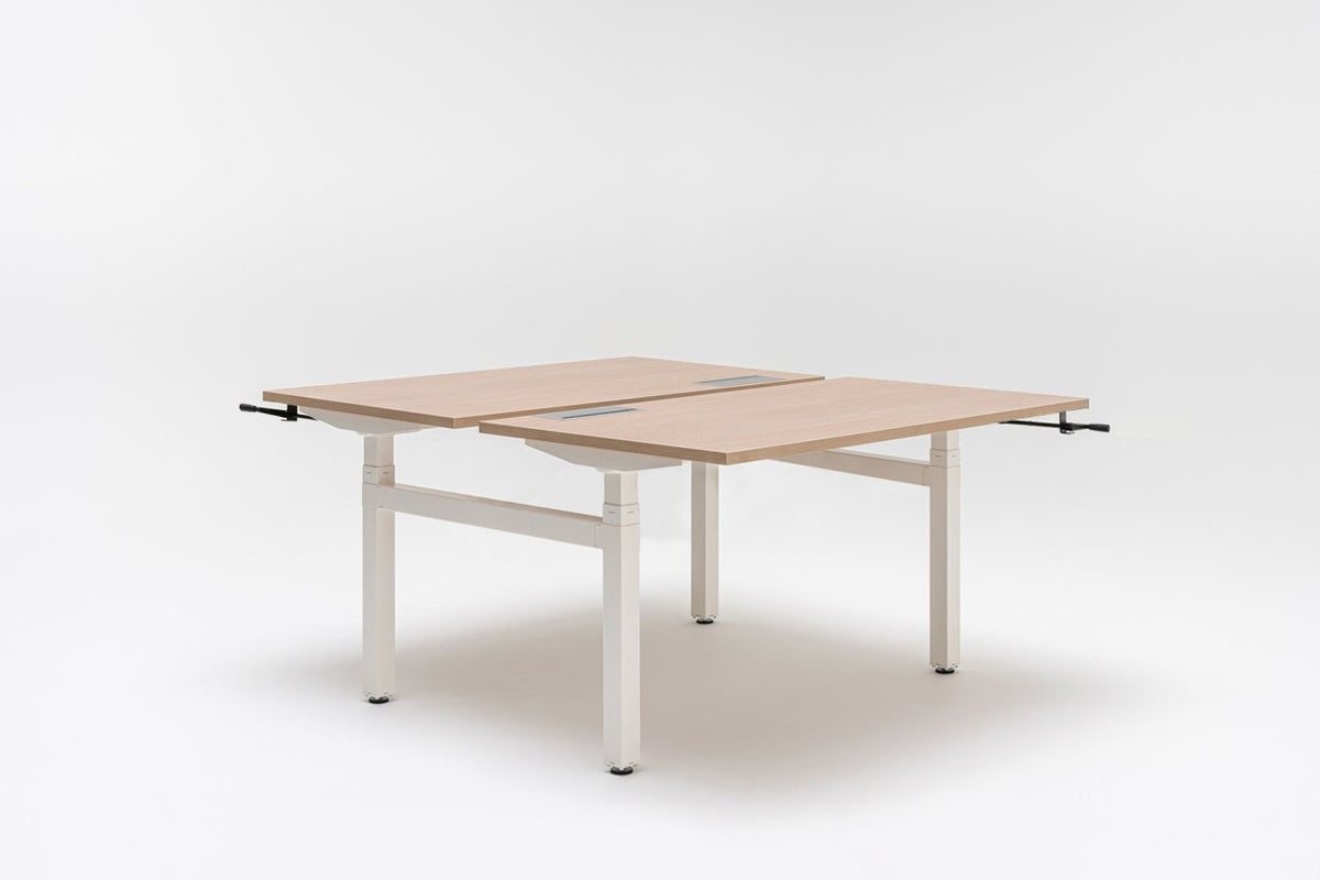 Doppelschreibtisch Ogi Drive Bench von Mdd mit Tischplatte in Honigeiche, schwarzem Metallgestell und seitlicher Kurbel zur Höhenverstellung.