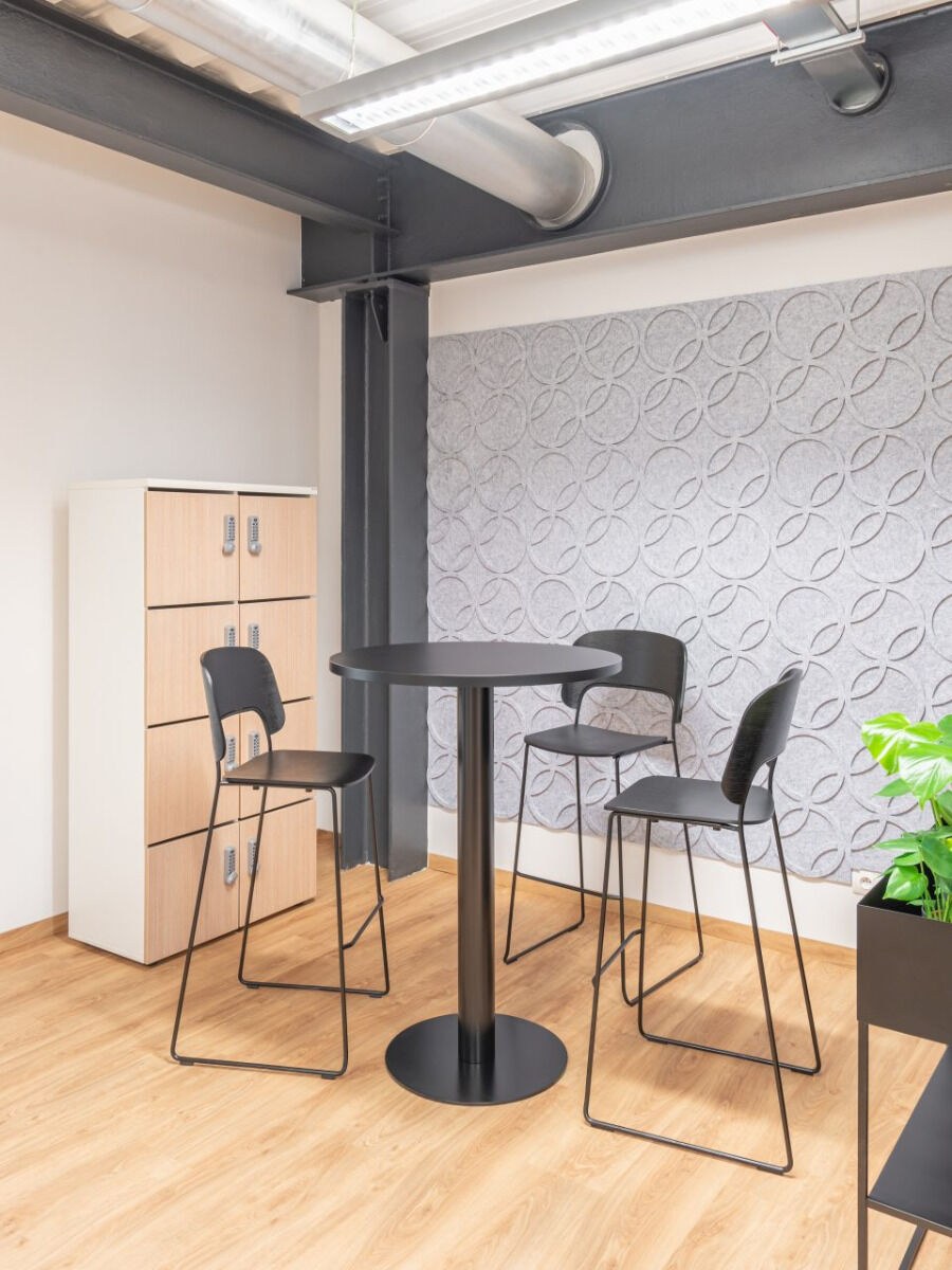 Runder Hochtisch Tack von Mdd in Honigeiche mit schwarzer Metallsäule und Tellerfuss, freistehend im Innenraum abgebildet.