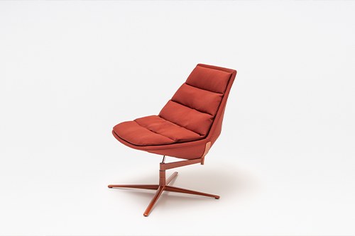 Ziegelroter Loungesessel mit gepolstertem Sitz, drapiertem Kissen und Aluminium-Drehfuss auf vier Sternbeinen, Frontalansicht.