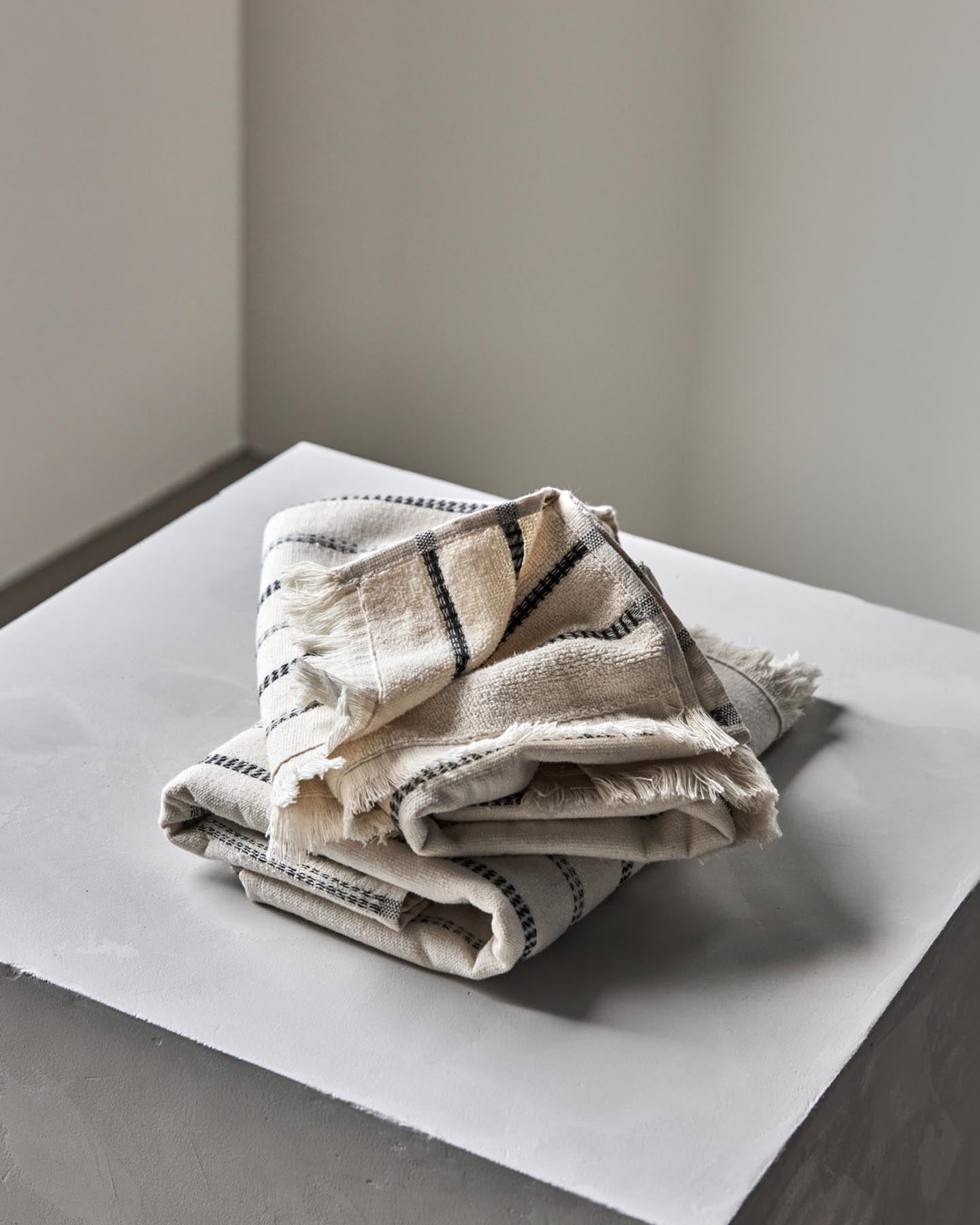 Verleihen Sie Ihrem Badezimmer mit dem eleganten Handtuch-Set MKTrue von Meraki in Off-White und Schwarz einen Hauch von Luxus und Stil.