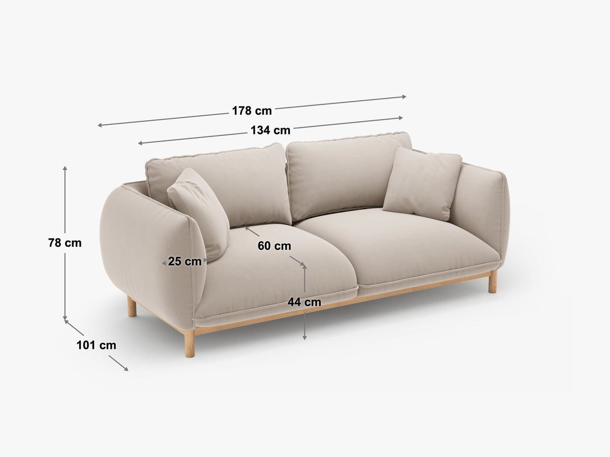 Ada 2er Sofa von Micadoni in Mandel beige mit gepolstertem Velours-Bezug, geschwungener Rückenlehne und sichtbaren Buchenholzbeinen.