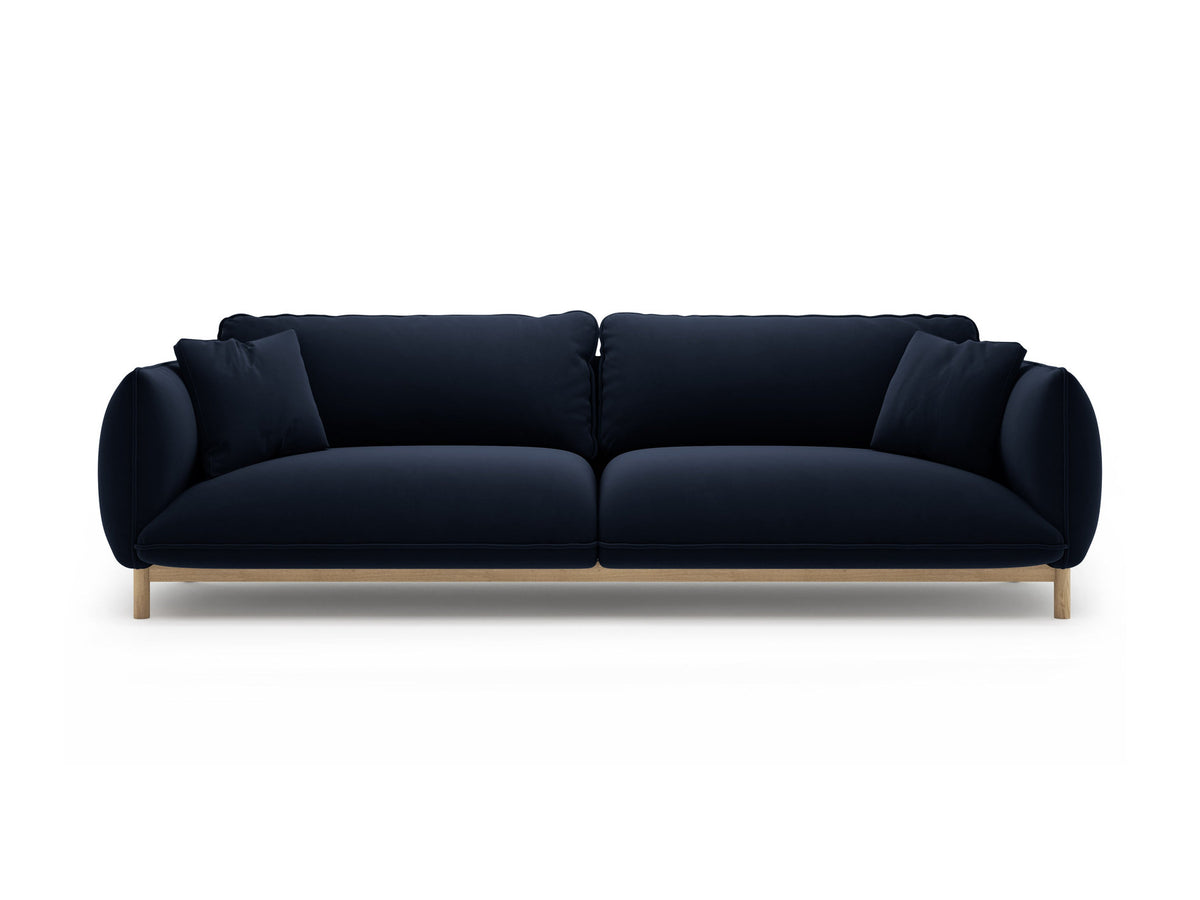 Vierersofa Ada von Micadoni in Mandel beige mit Casino-Stoffbezug, gerundeten Armlehnen und sichtbarem Buchenholzgestell auf Holzbeinen.