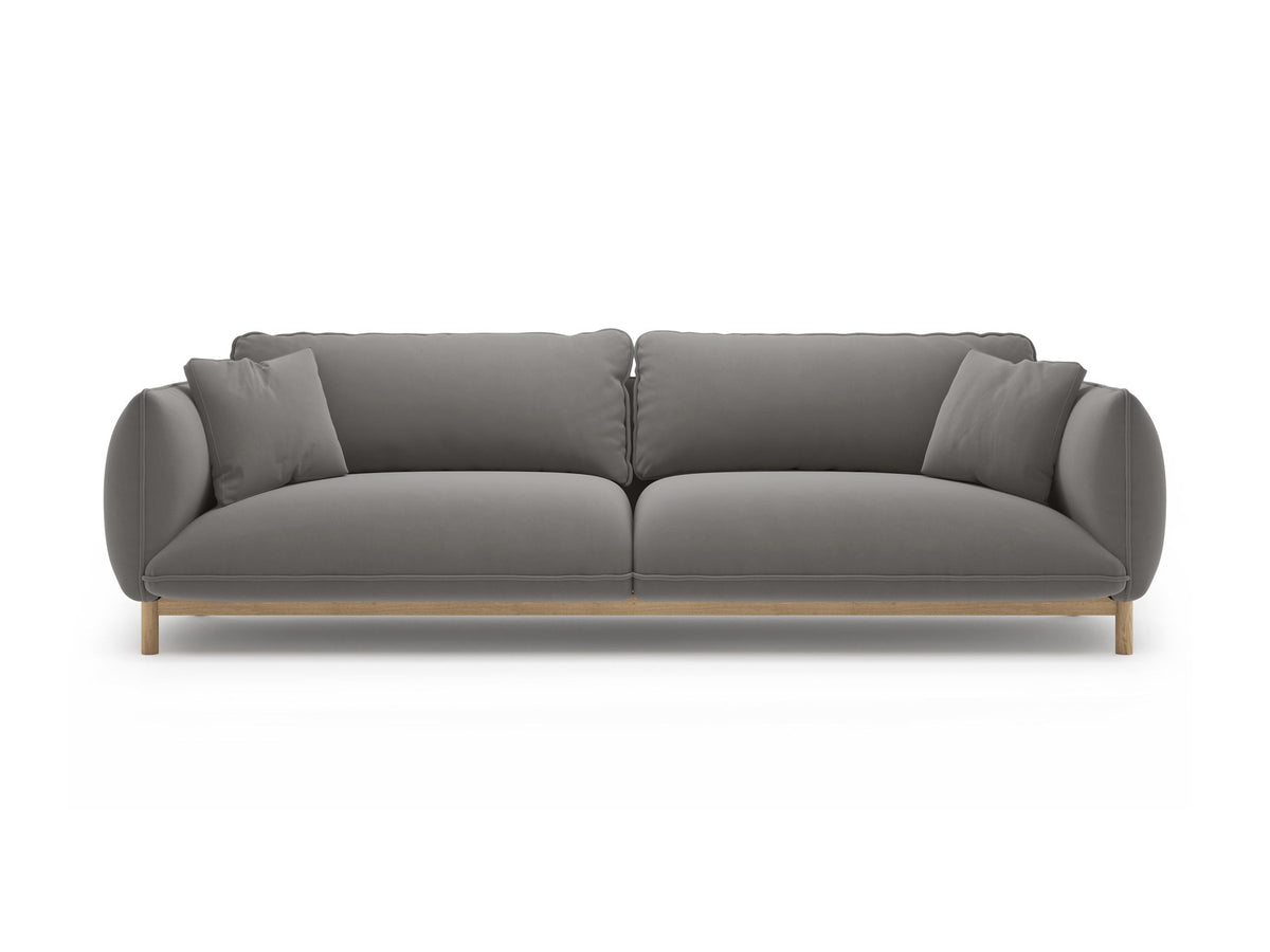 Vierersofa Ada von Micadoni in Mandel beige mit Casino-Stoffbezug, gerundeten Armlehnen und sichtbarem Buchenholzgestell auf Holzbeinen.