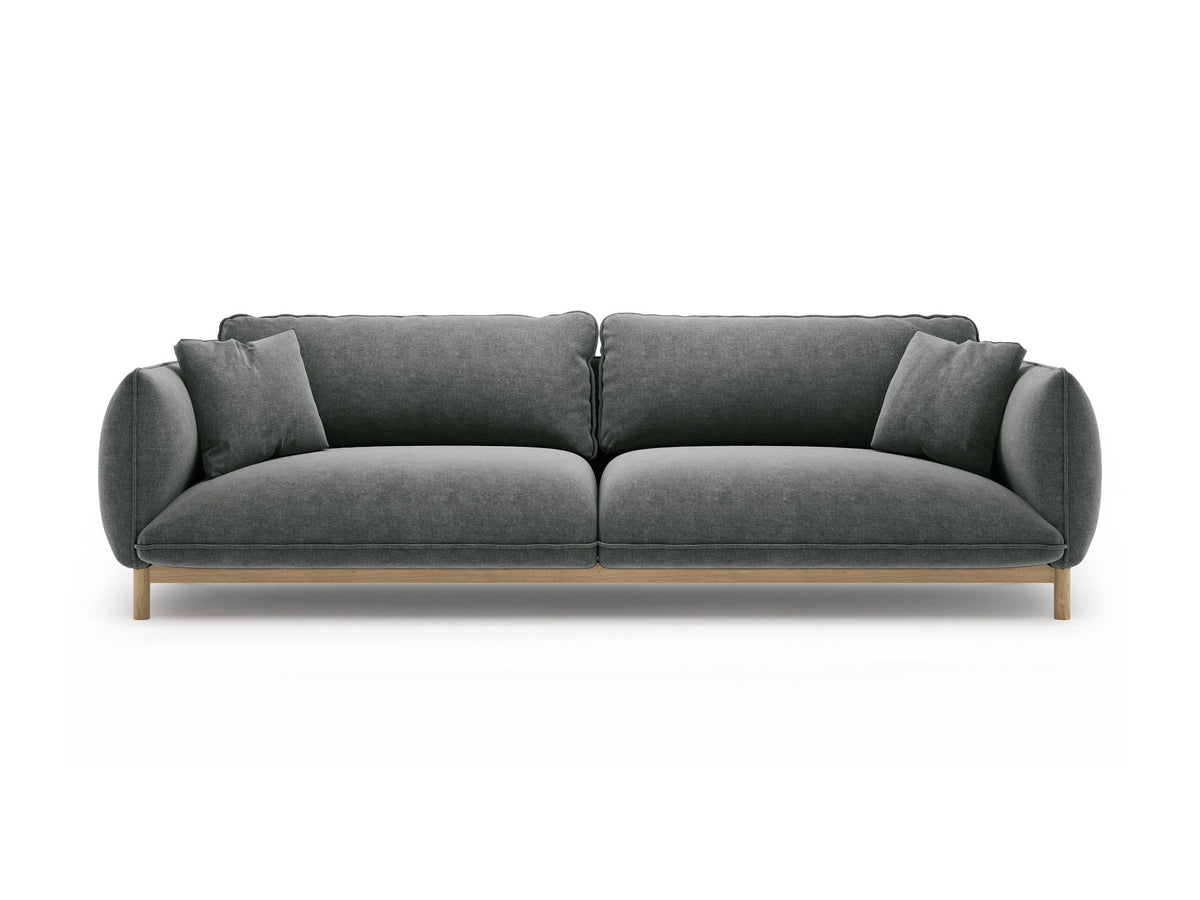 Vierersofa Ada von Micadoni in Mandel beige mit Casino-Stoffbezug, gerundeten Armlehnen und sichtbarem Buchenholzgestell auf Holzbeinen.