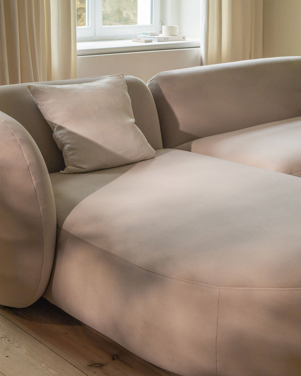 Weisser Armsessel Kate von Micadoni mit Bouclé-Stoffbezug, schwarzen Kunststoffbeinen und gepolsterter Rückenlehne, Frontalansicht.