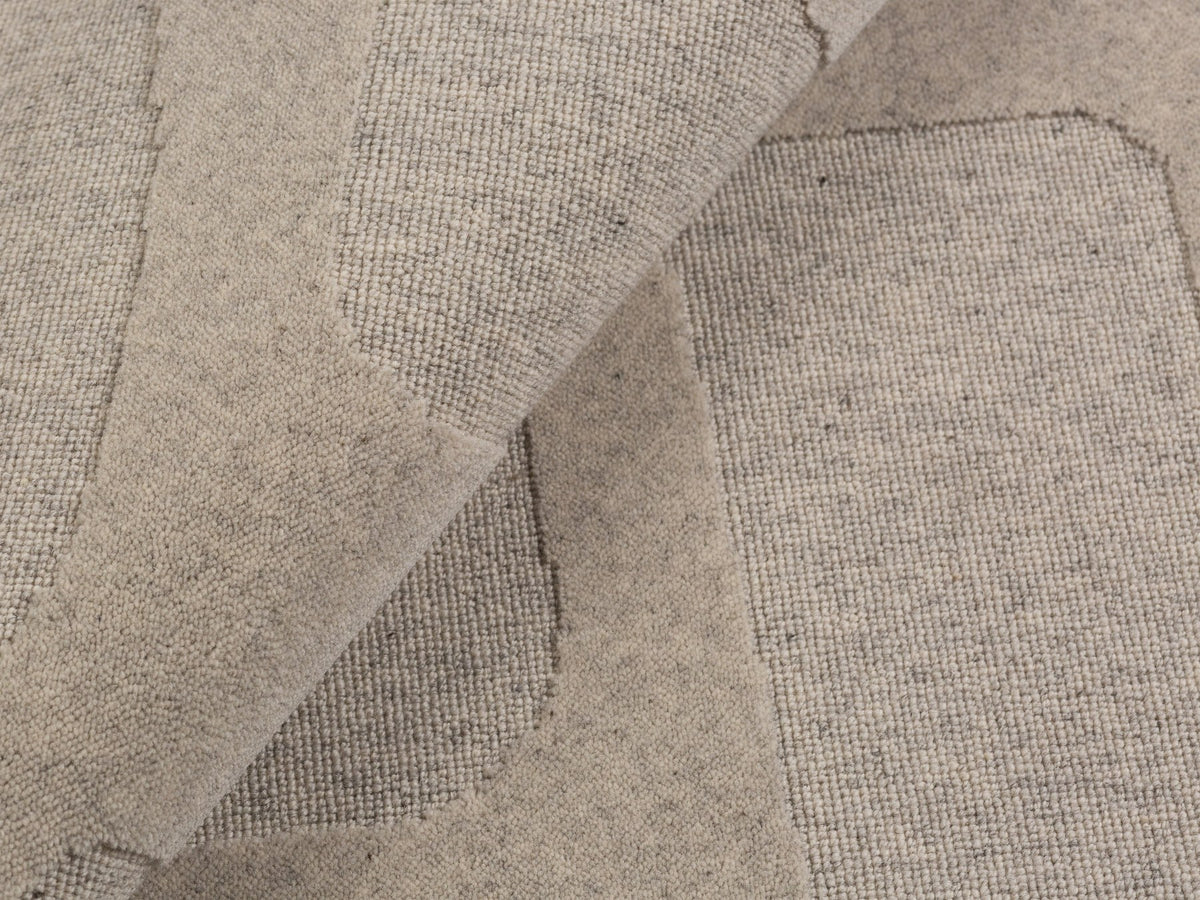Hellgrauer rechteckiger Teppich Archipelagio von Micadoni aus 100% Wolle mit dichtem Flor und sauber verarbeiteten Kanten auf hellem Boden.