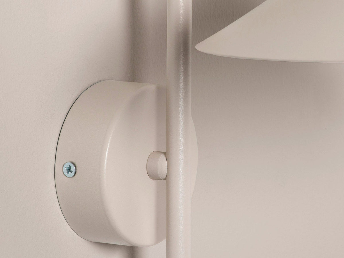 Wandlampe Nocte von Micadoni in Burgundfarben, konische Form aus mattem Metall, montiert an einer hellen Wand im Wohnraum.