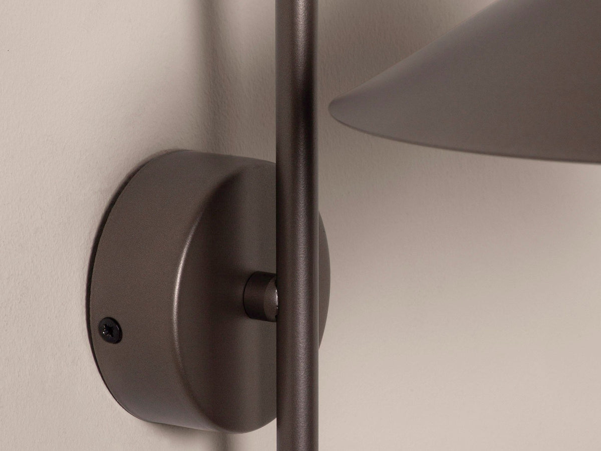 Wandlampe Nocte von Micadoni in Burgundfarben, konische Form aus mattem Metall, montiert an einer hellen Wand im Wohnraum.