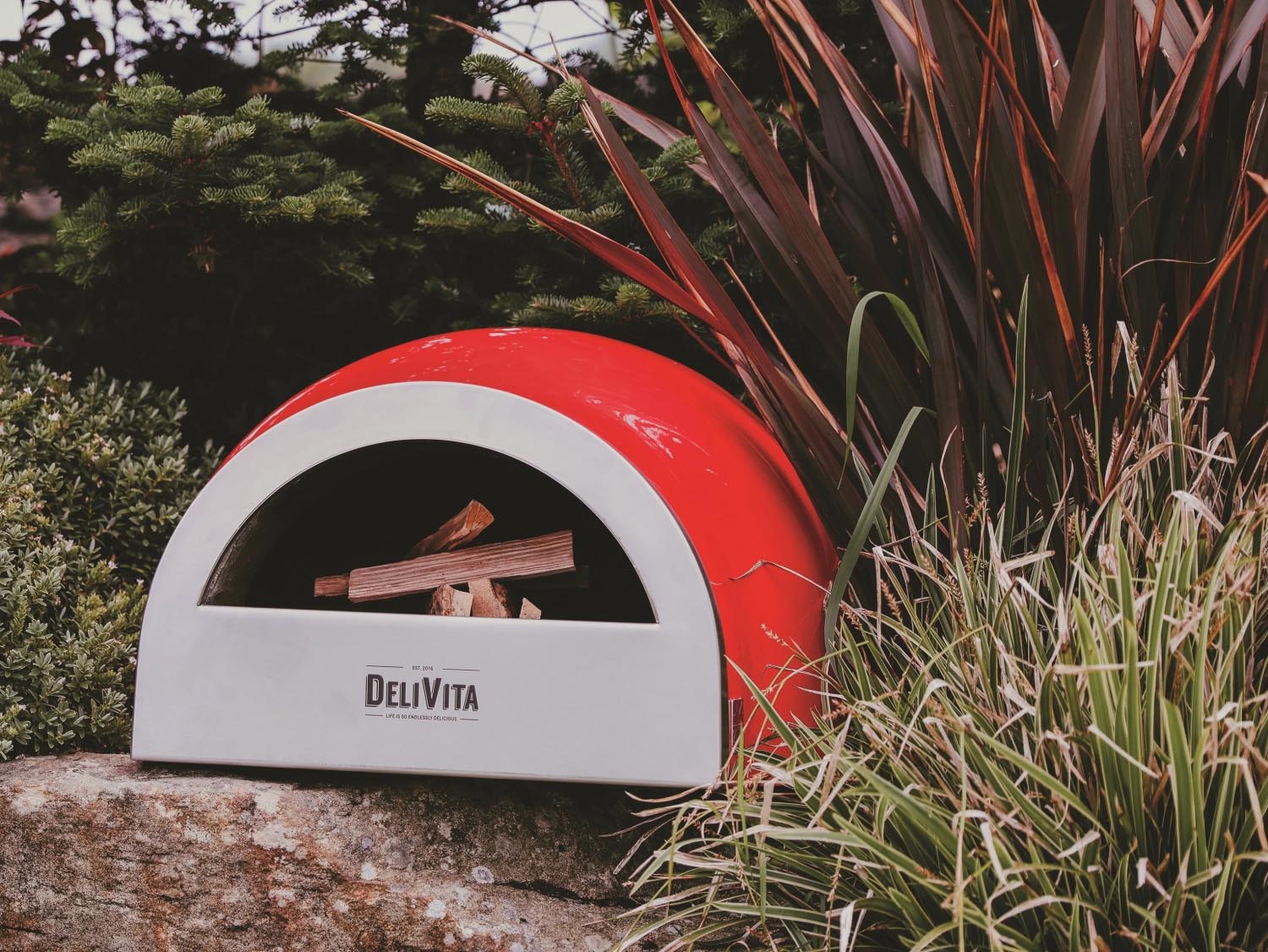 Der tragbare Delivita Ofen in Chilirot, perfekt für Pizza und mehr, kombiniert Stil und Funktionalität in einem kompakten Design.