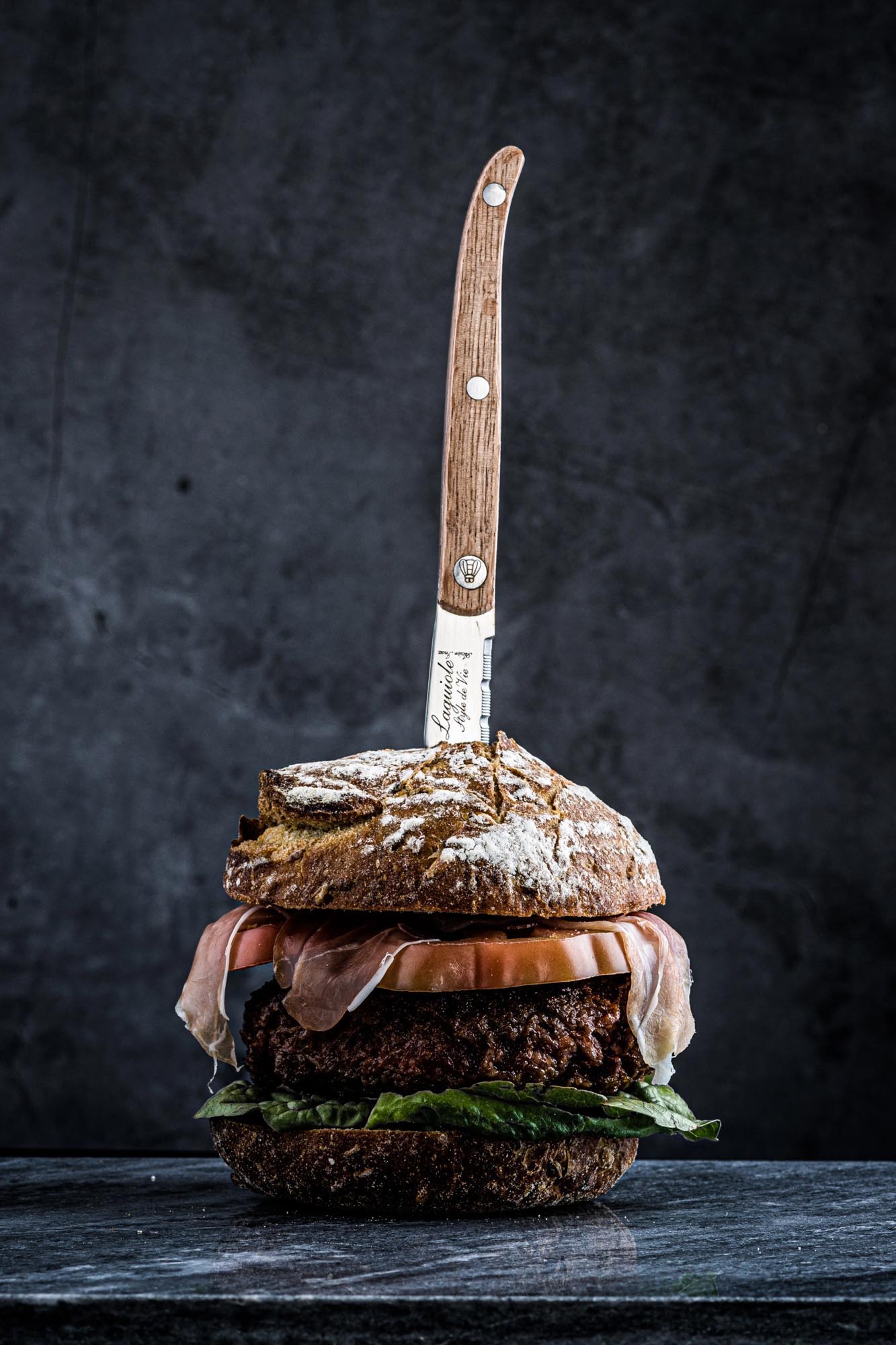 Elegantes Laguiole Steakmesser mit Eichenholzgriff und gezackter Klinge, ideal für präzises Schneiden von Fleisch.