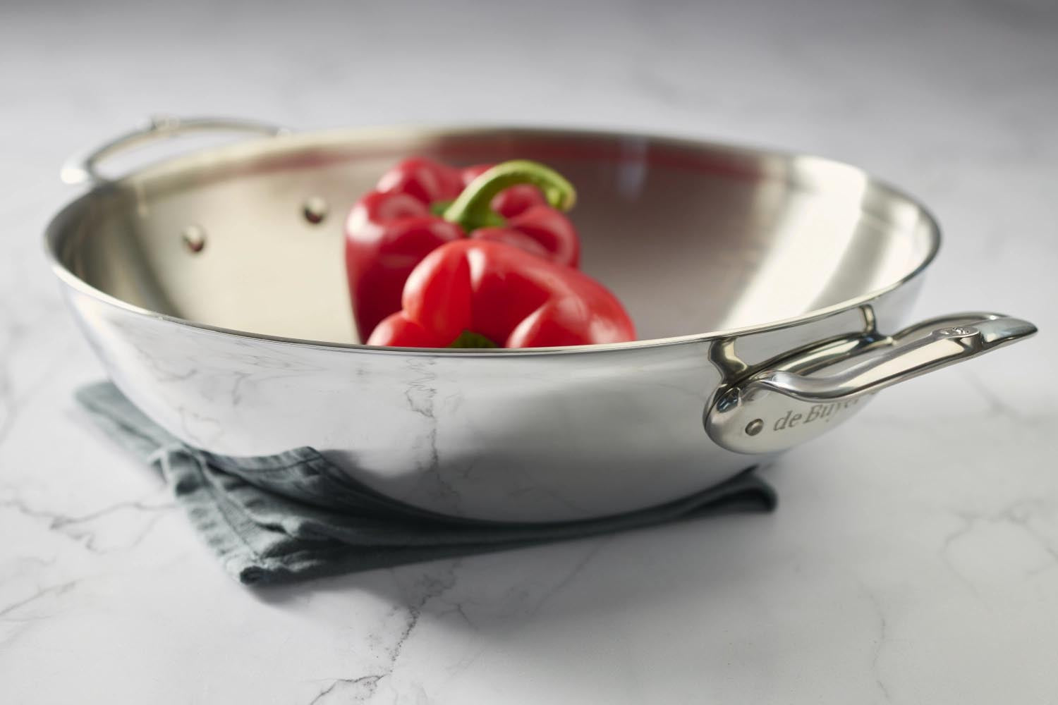 Eleganter Edelstahl-Wok von de Buyer, 32 cm, mit zwei Griffen, perfekt für gleichmässiges Garen und vielseitige Kochmöglichkeiten.