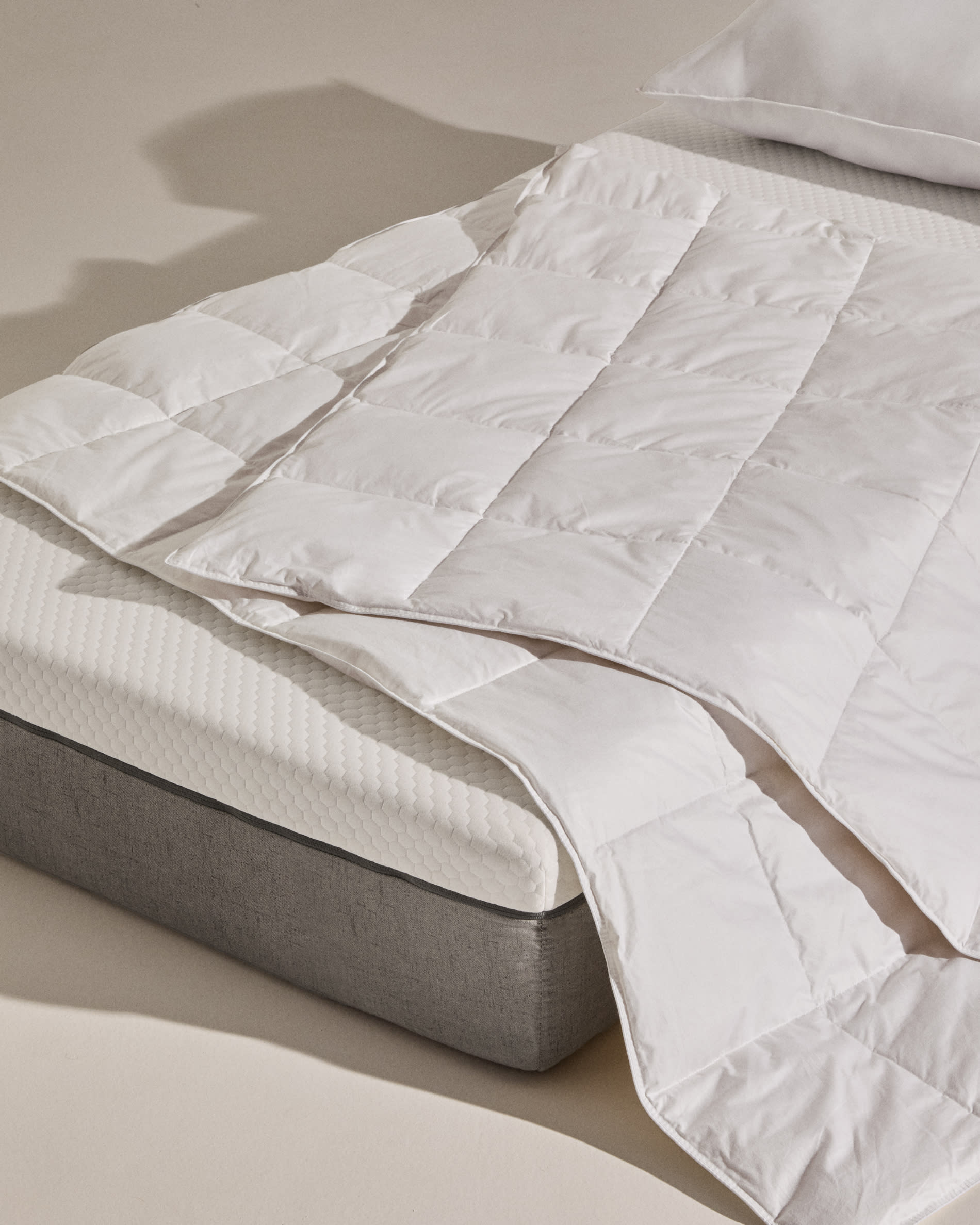 Hochwertige Steppdecke Atra mit 70% Daunen und 30% Federn, perfekt für 80/90 cm Betten, hergestellt in Spanien von Kave Home.