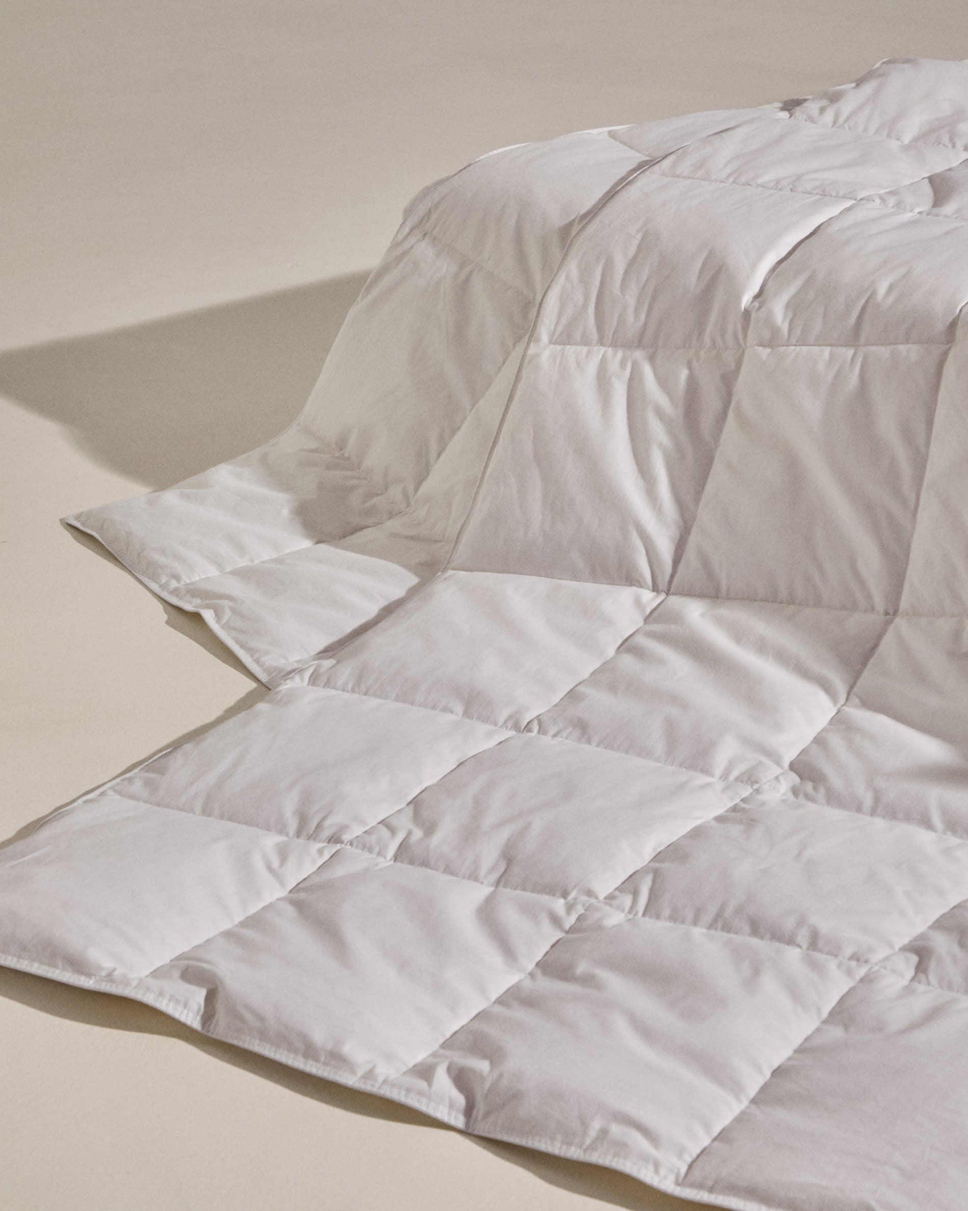 Hochwertige Steppdecke Atra mit 70% Daunen und 30% Federn, perfekt für 80/90 cm Betten, hergestellt in Spanien von Kave Home.