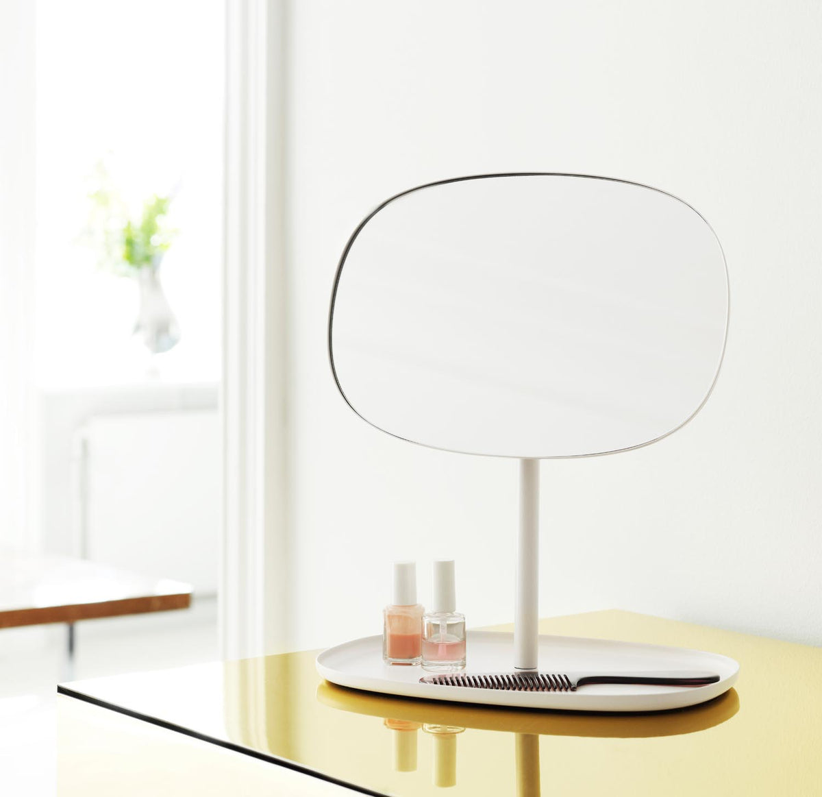 Tischspiegel Flip von Normann Copenhagen mit rundem Glasspiegel und Fuss aus beschichtetem Stahl in organischer Form, Farbe Schwarz.