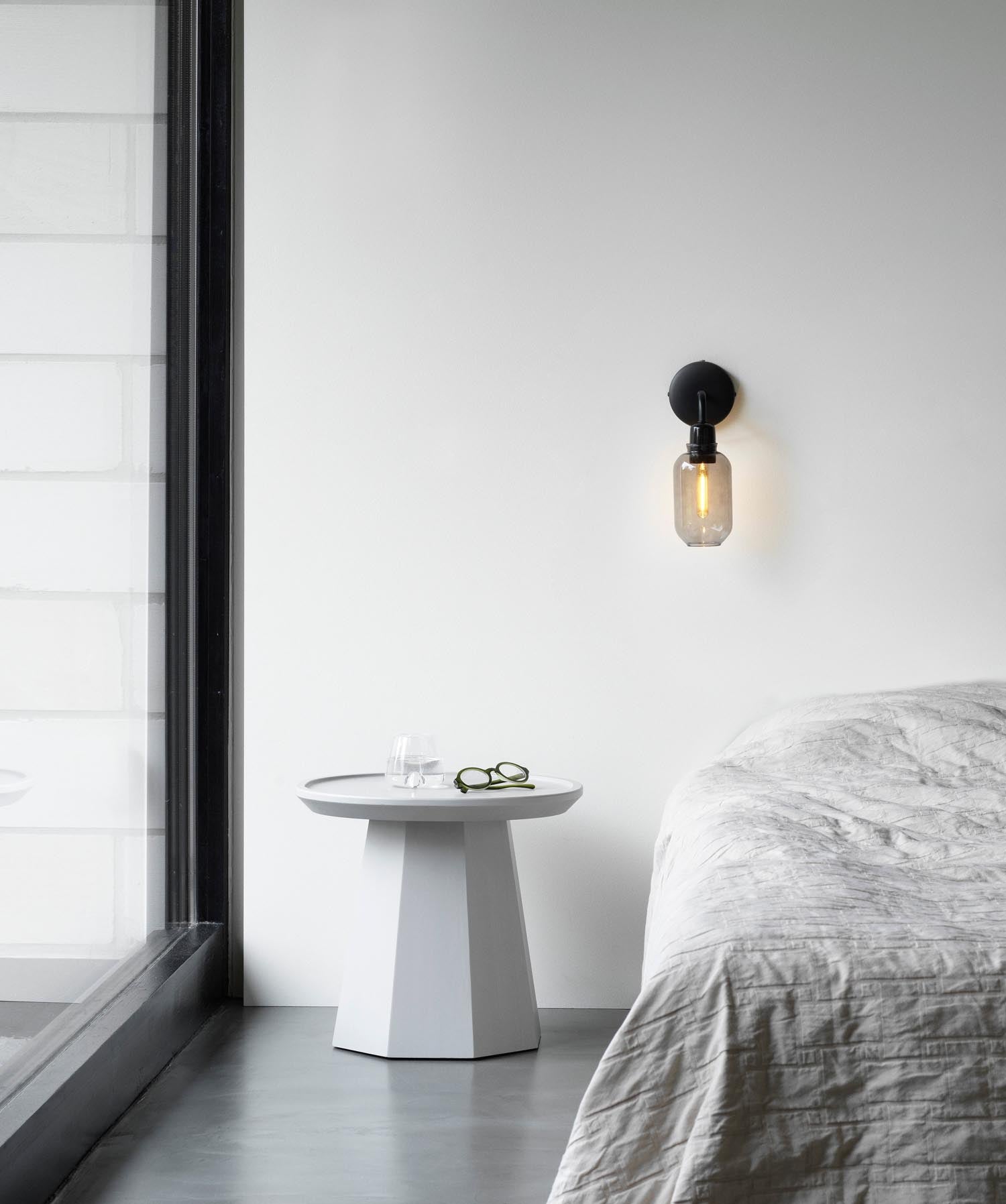 Die Amp Wandlampe von Normann Copenhagen in edlem Rauchschwarz kombiniert hochwertiges Glas und Marmor für ein modernes Ambiente.