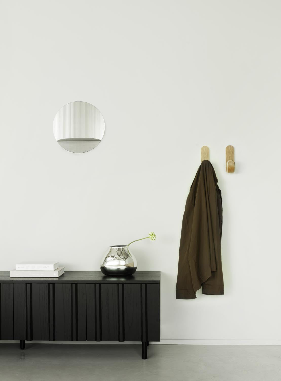 Runder Wandspiegel aus Spiegelglas mit grauem Stahlrahmen und integriertem Ablageboden, minimalistisches geometrisches Design von Normann Copenhagen.