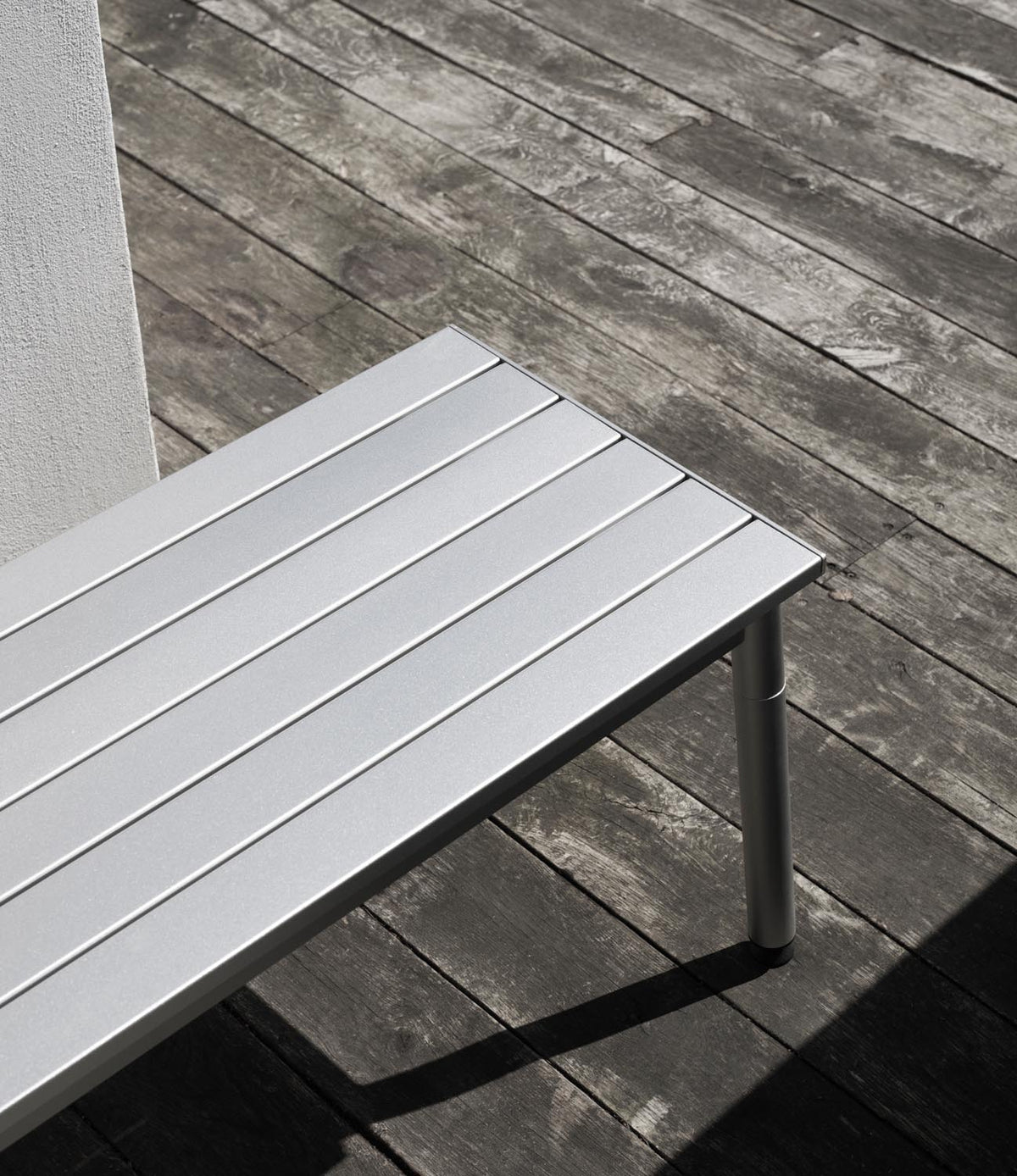 Gartenbank Ex von Normann Copenhagen aus eloxiertem Aluminium mit schlanken, leicht versetzten Profilen und vier angewinkelten Beinen.