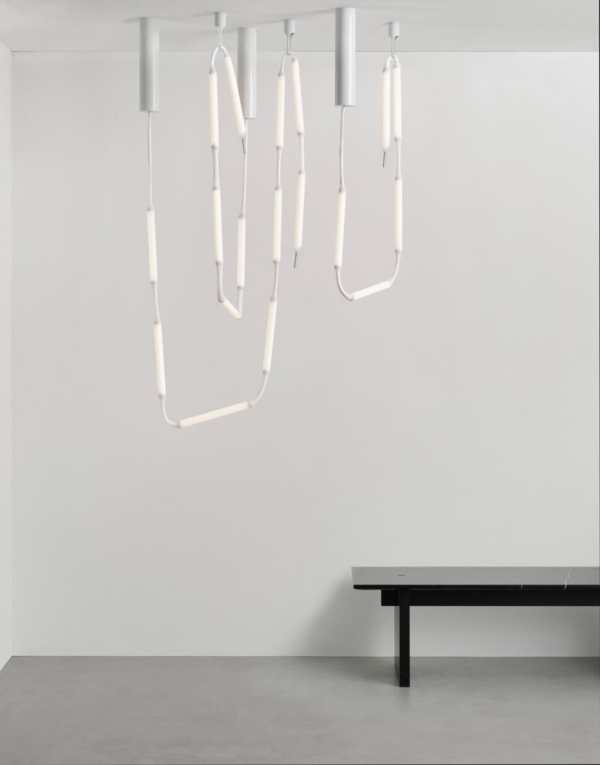 Weisse Pendelleuchte Reb Lampe 8 aus PET und PMMA mit netzartigem Acrylrohr, acht LED-Module an einem langen Kabel hängend.