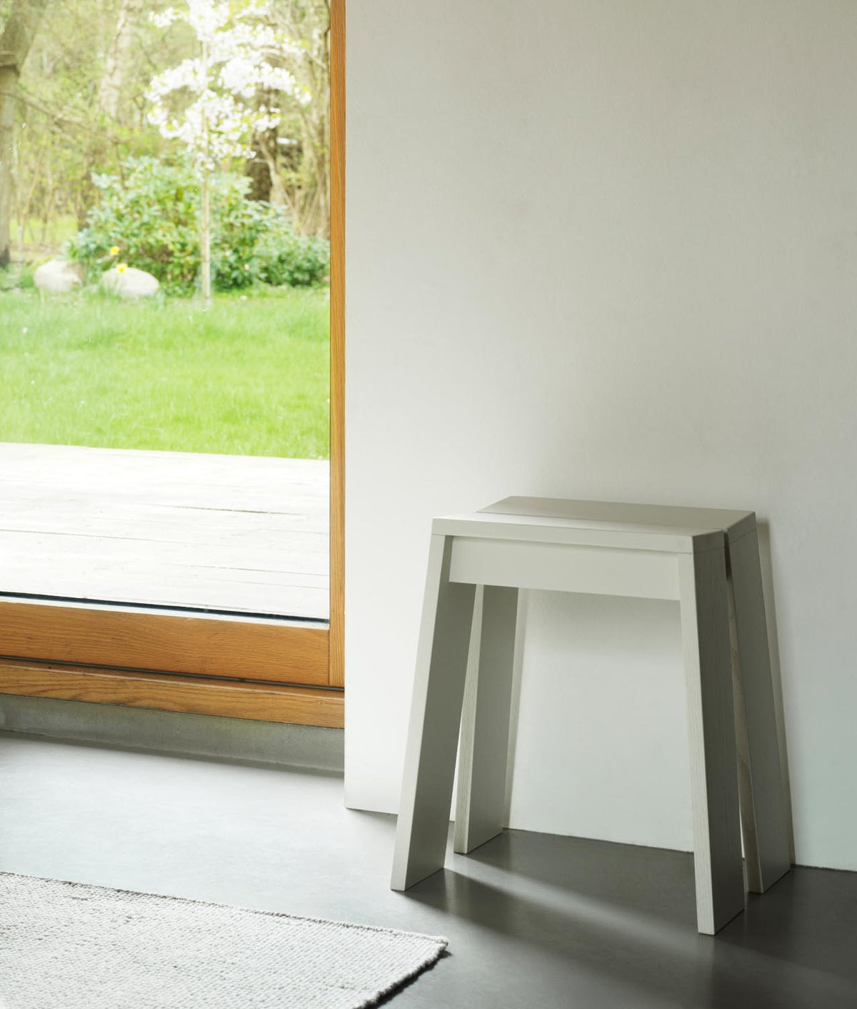 Hocker Let von Normann Copenhagen aus lackierter Eiche mit zwei parallelen, leicht geneigten Holzplanken als Sitzfläche und Beinen.