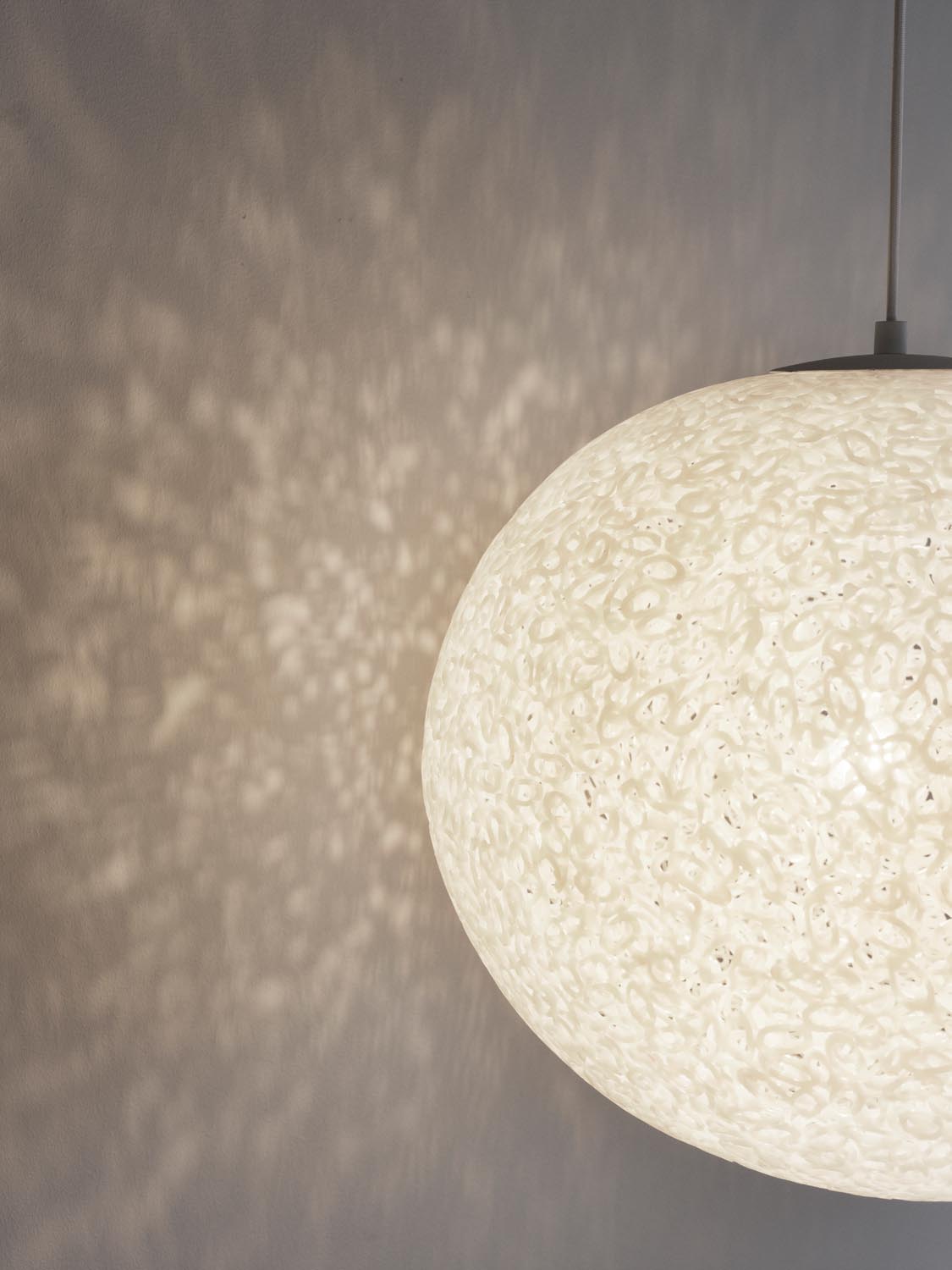 Weisse Pendelleuchte Act Ø60 von Normann Copenhagen mit transparentem Lampenschirm aus verschmolzenen, oval geschnittenen PE-Rohrringen.