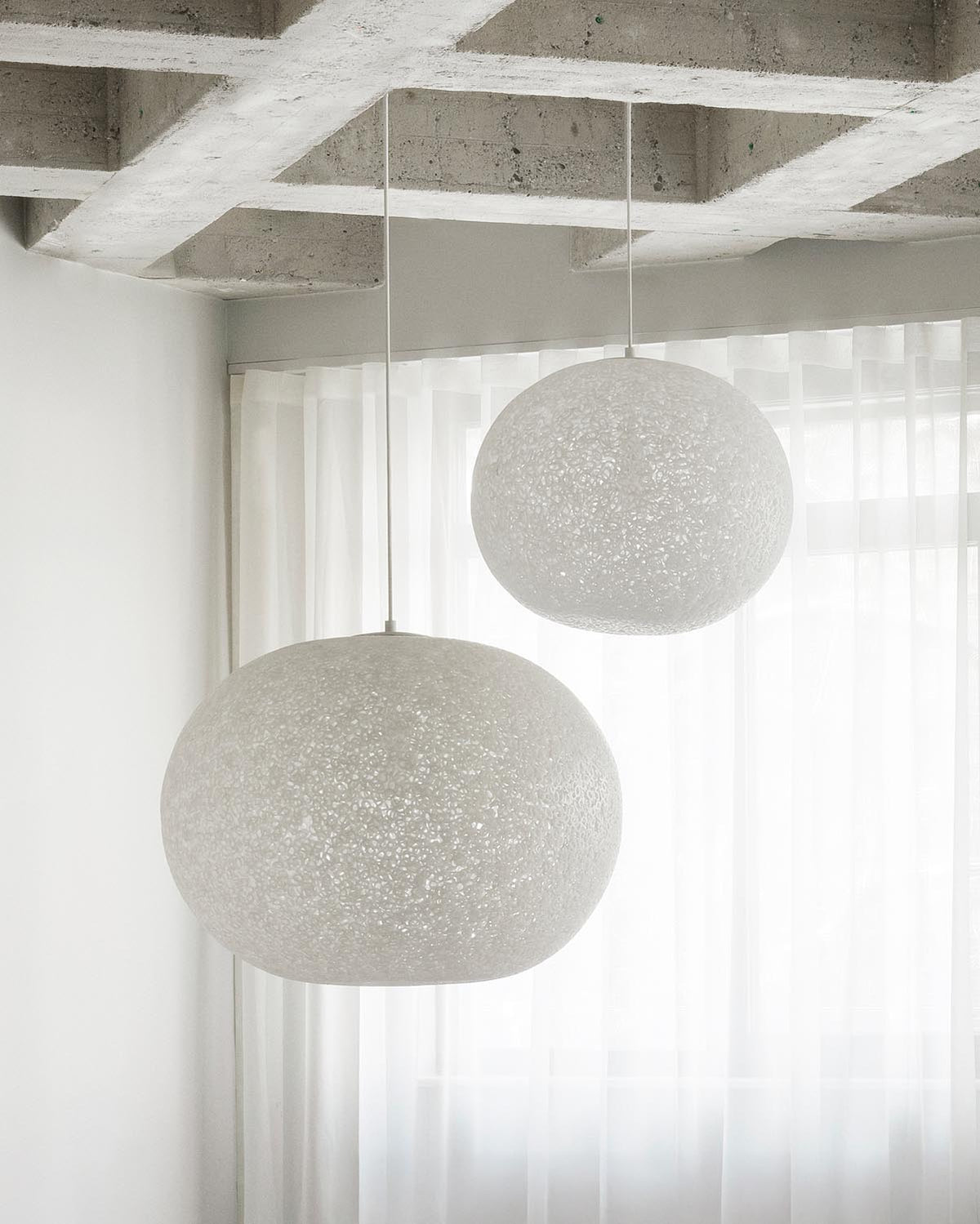 Weisse Pendelleuchte Act Ø60 von Normann Copenhagen mit transparentem Lampenschirm aus verschmolzenen, oval geschnittenen PE-Rohrringen.