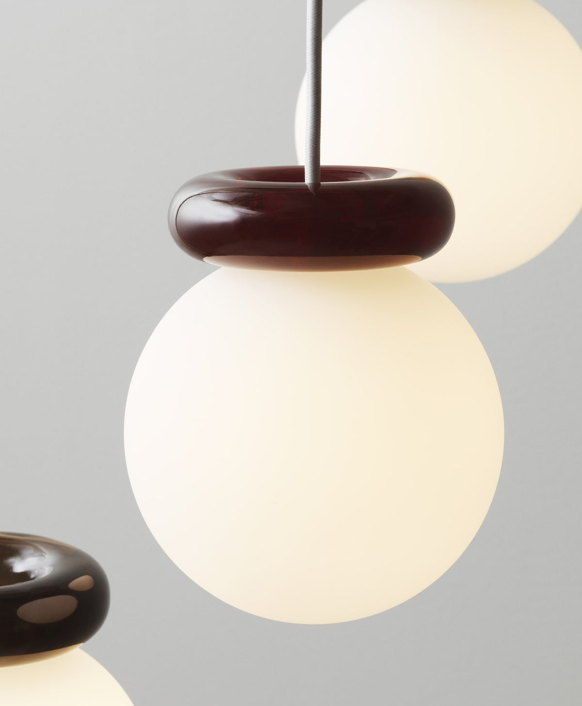 Pendelleuchte Hinx von Normann Copenhagen in Dunkelbraun, Lampenschirm aus Opalglas mit ringförmigem Kunstharzsockel.