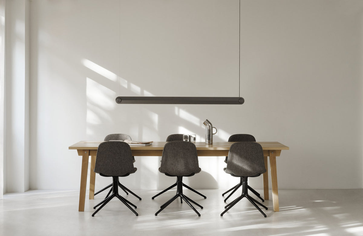 Form Drehstuhl von Normann Copenhagen mit gepolsterter Schale aus Polypropylen auf Drehsockel aus schwarzem Aluminium mit vier Rädern.