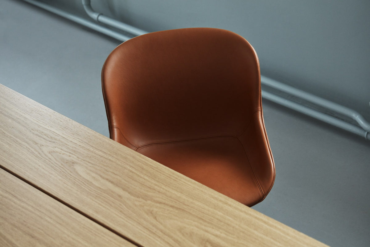 Drehstuhl Hyg von Normann Copenhagen mit gepolsterter Sitzschale in Braun, organisch geschwungener Form und vierstrahligem Aluminiumfuss.
