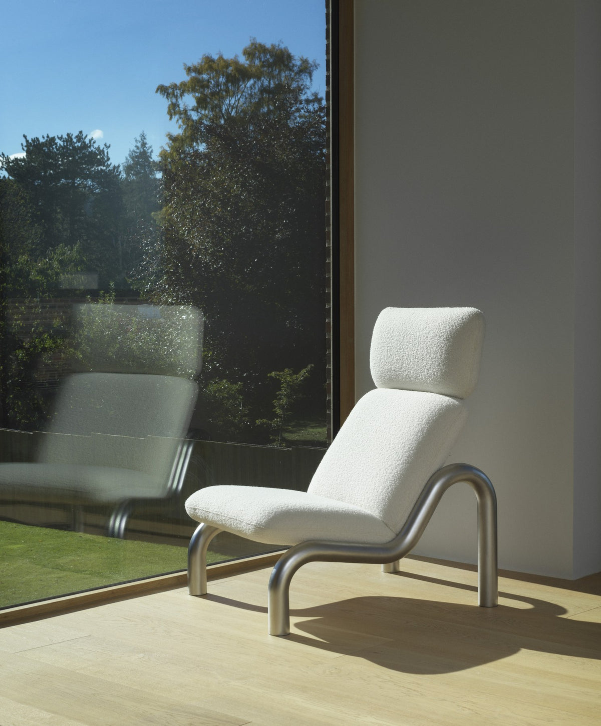 Tube Lounge-Sessel von Normann Copenhagen in Weiss, mit gebogenem Edelstahl-Rohrgestell und gepolstertem Sitz sowie hoher Rückenlehne.