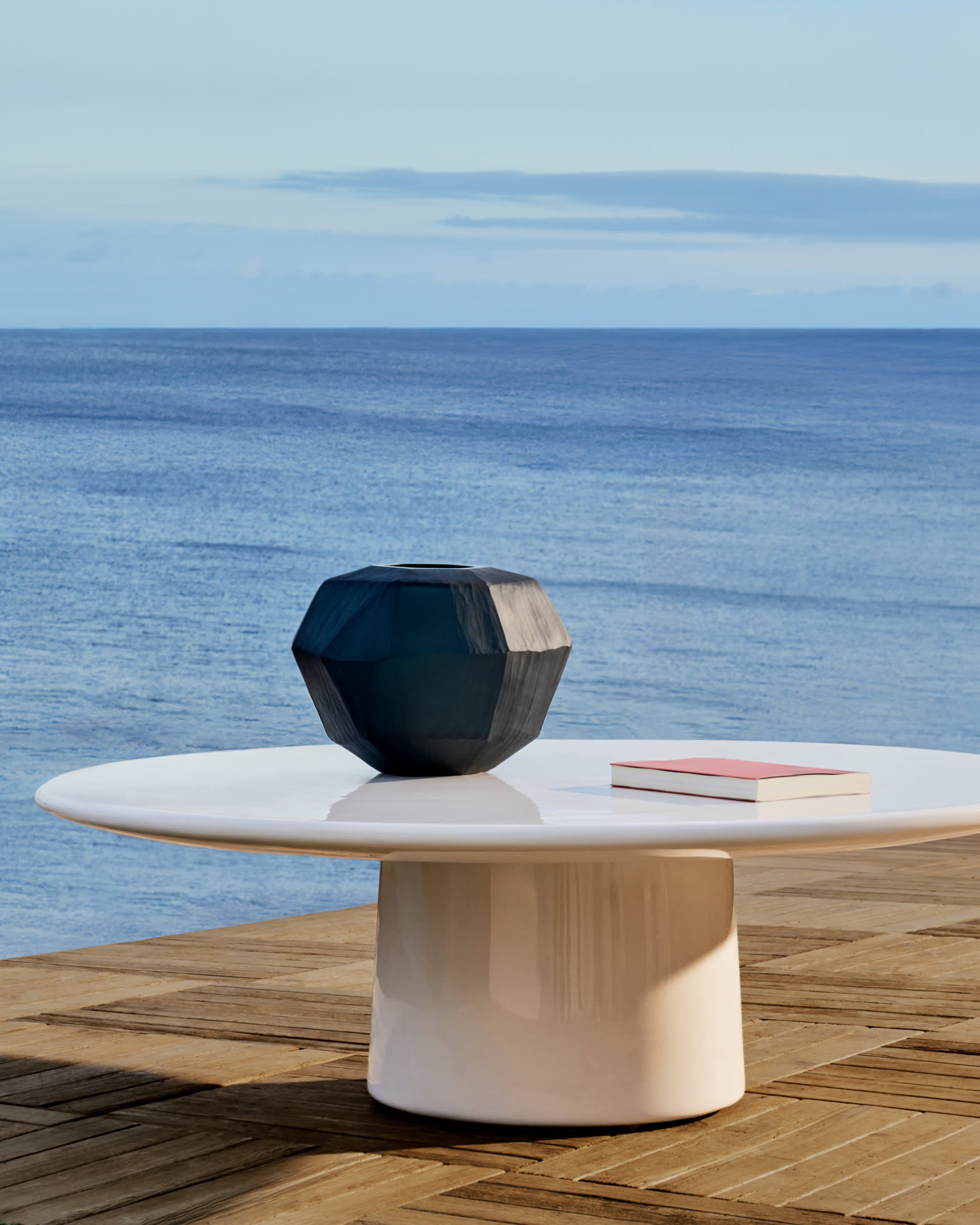 Eleganter Couchtisch aus wetterfestem Zement, Ø 110 cm, mit einzigartigem, glänzend weissem Finish für stilvolle Aussenbereiche.