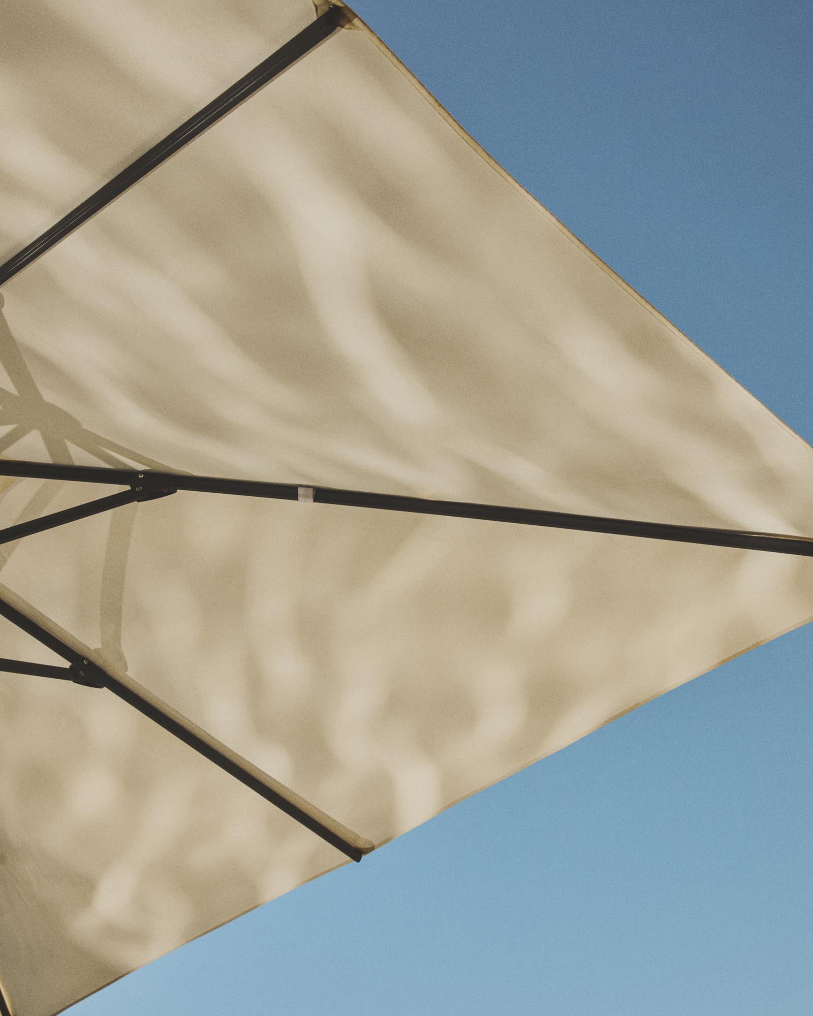 Eleganter Sonnenschirm Noli in Beige mit grünem Aluminiumgestell, perfekt für schattige Oasen im Freien und stilvolle Terrassengestaltung.