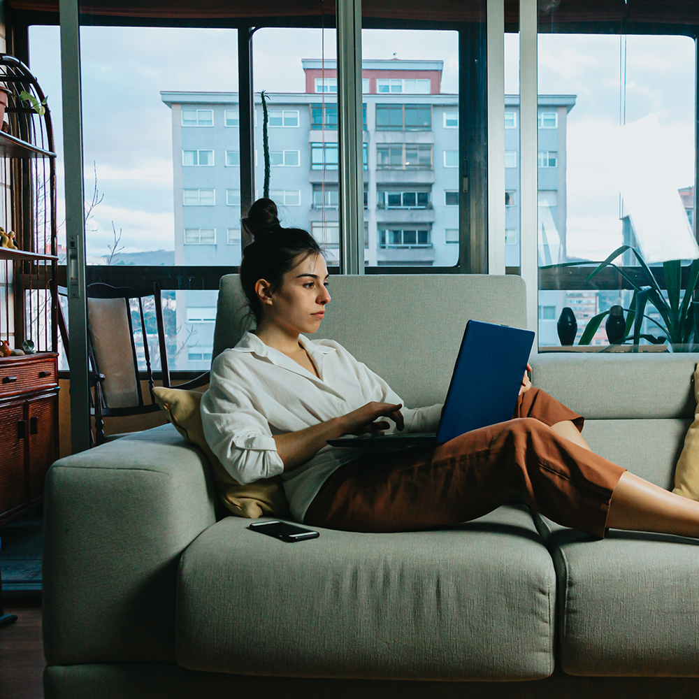 Frau sitzt auf dem Sofa mit dem Laptop