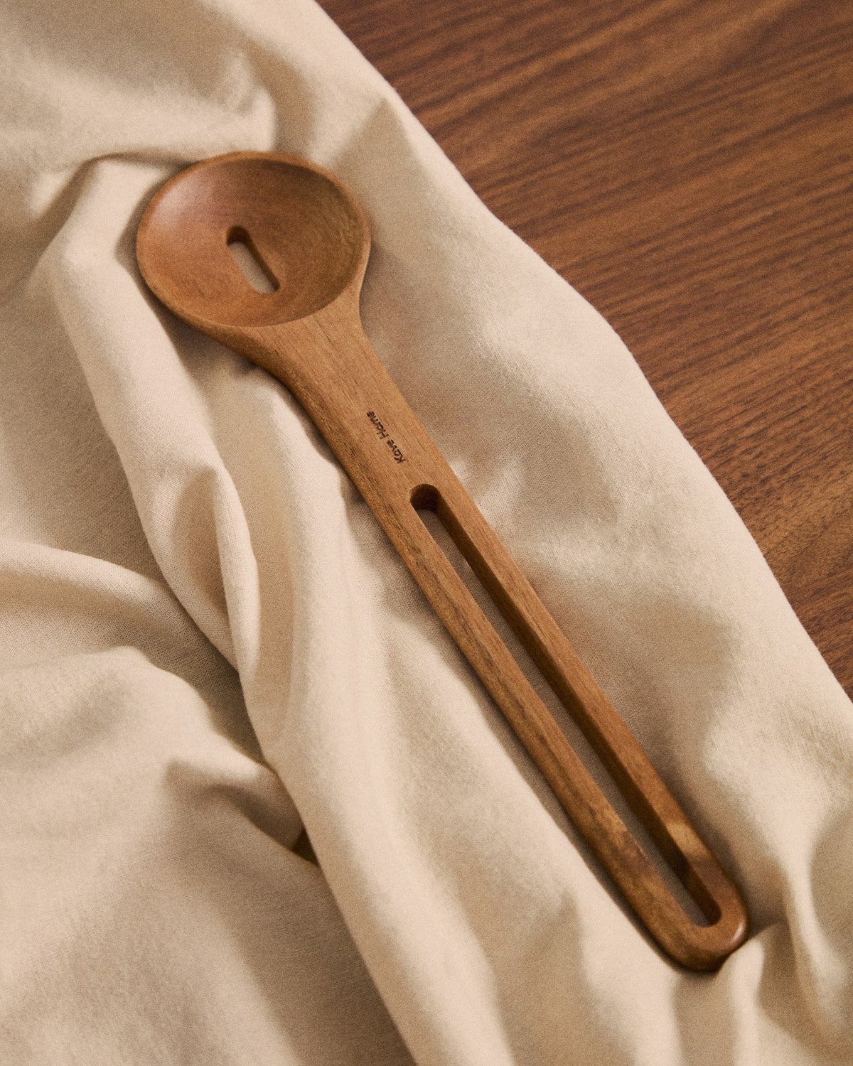 Küchenaccessoire Blera aus lackiertem Akazienholz in Naturton, längliche Form mit Loch zum Aufhängen, sichtbare natürliche Holzmaserung.