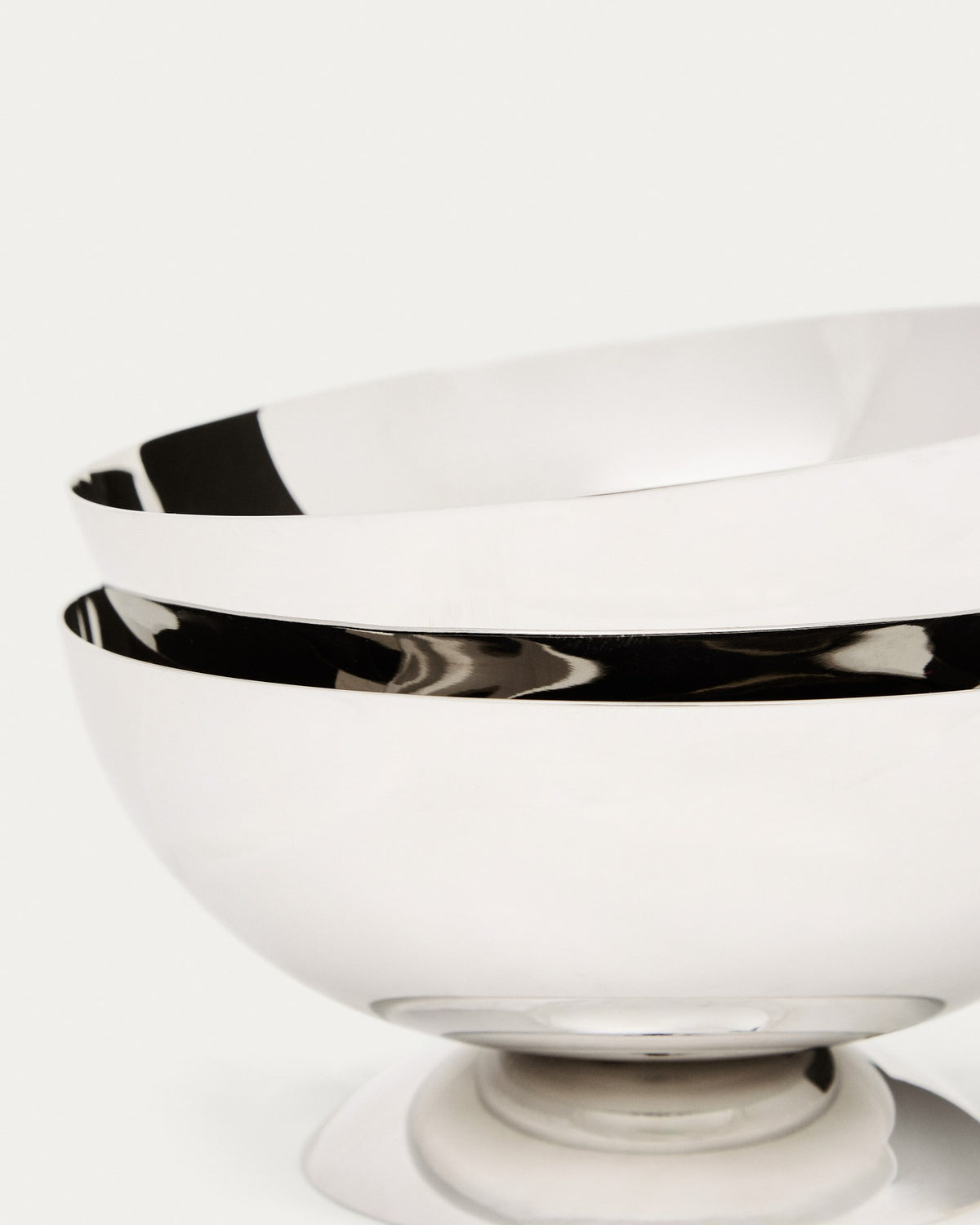 Zwei runde Schalen aus glänzendem, rostfreiem Edelstahl in Silber, stapelbar, mit glatter Oberfläche und schlichter Form.