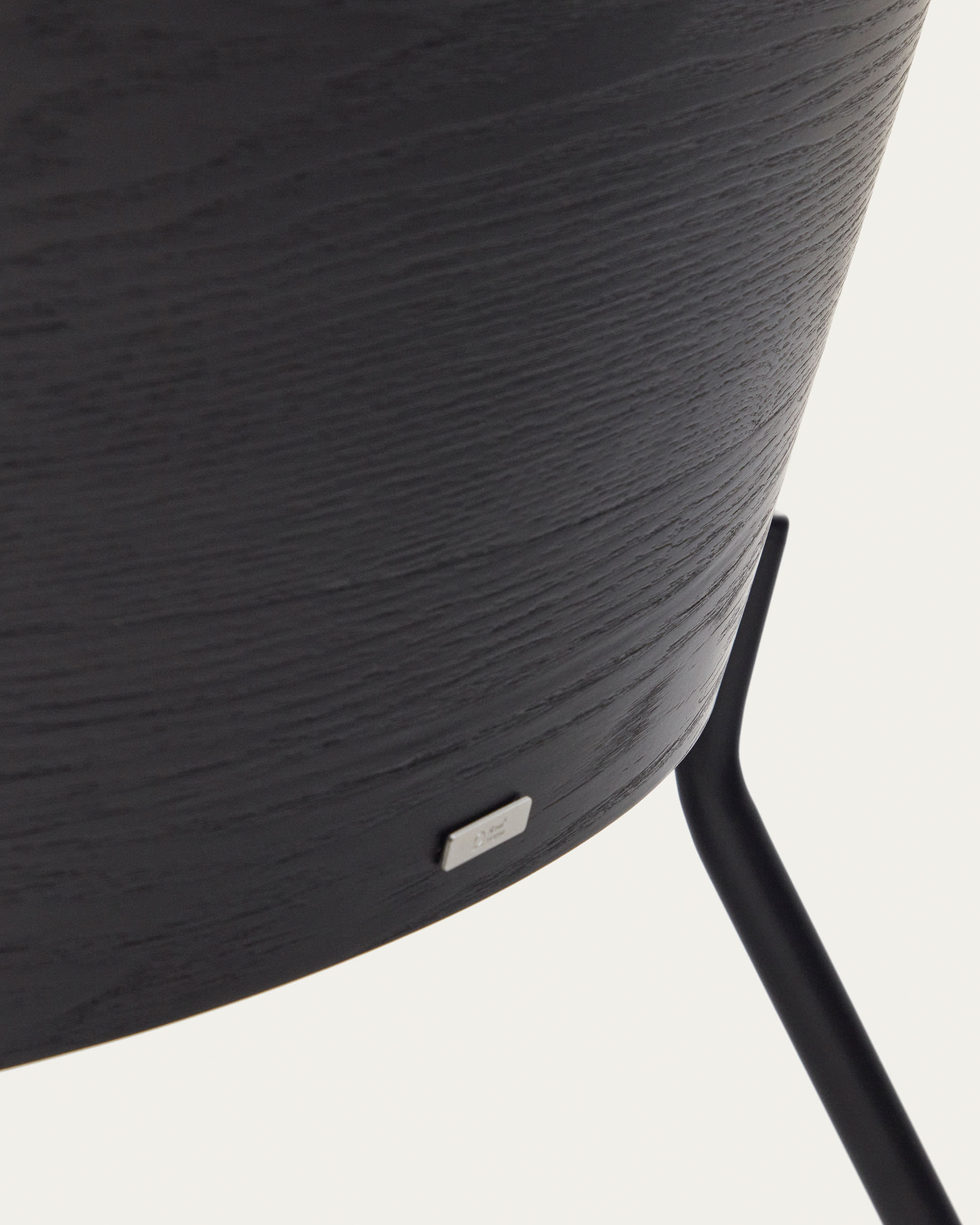 Moderner Eamy Sessel in sanftem Hellgrau, kombiniert mit edlem Eschenfurnier und robustem schwarzem Metallgestell – ideal für stilvolle Entspannung.