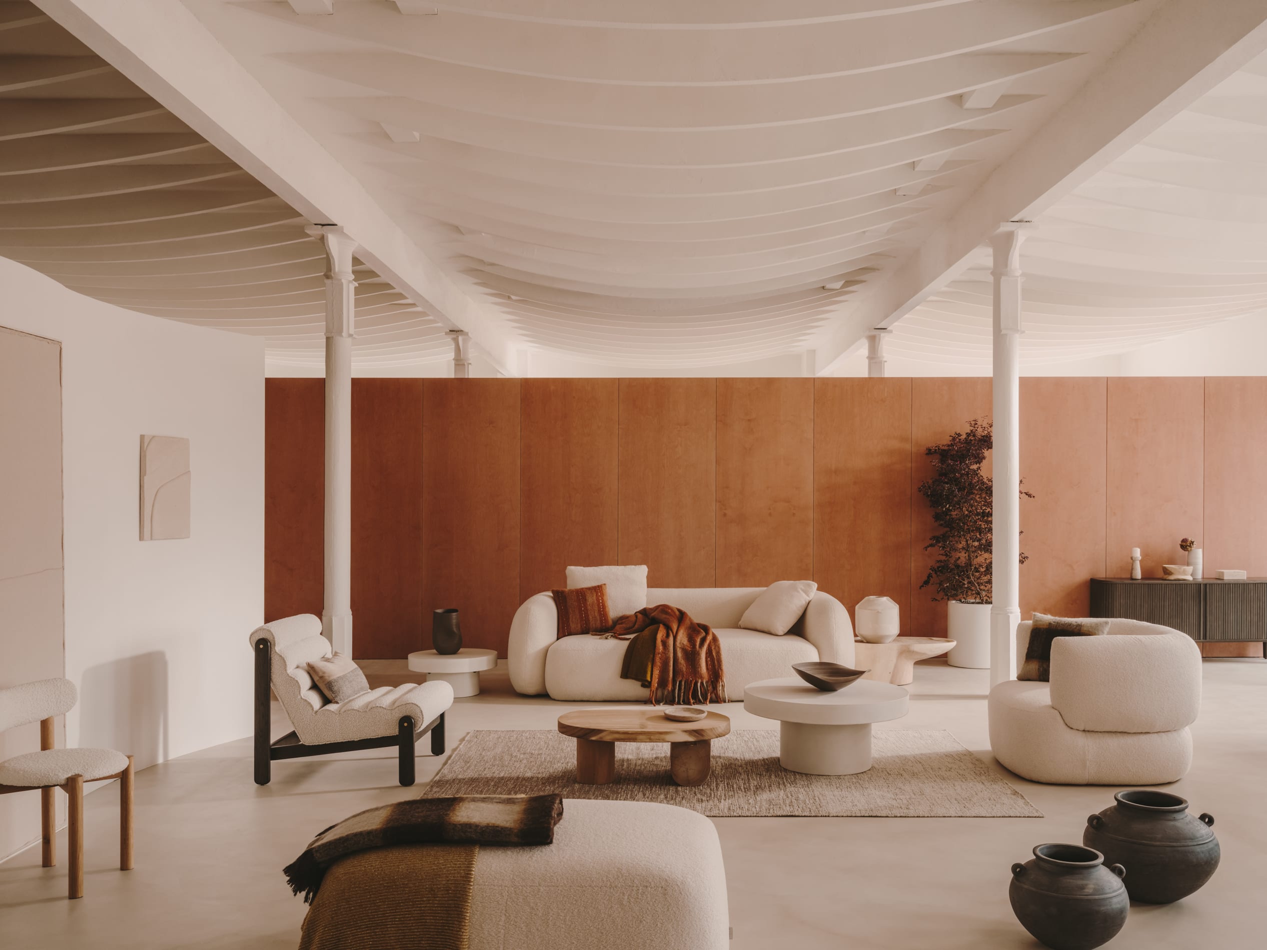 Eleganter Sessel Magira mit weissem Bouclé-Stoff und dunklem Eichenholzrahmen, ideal für stilvolle Wohnräume.