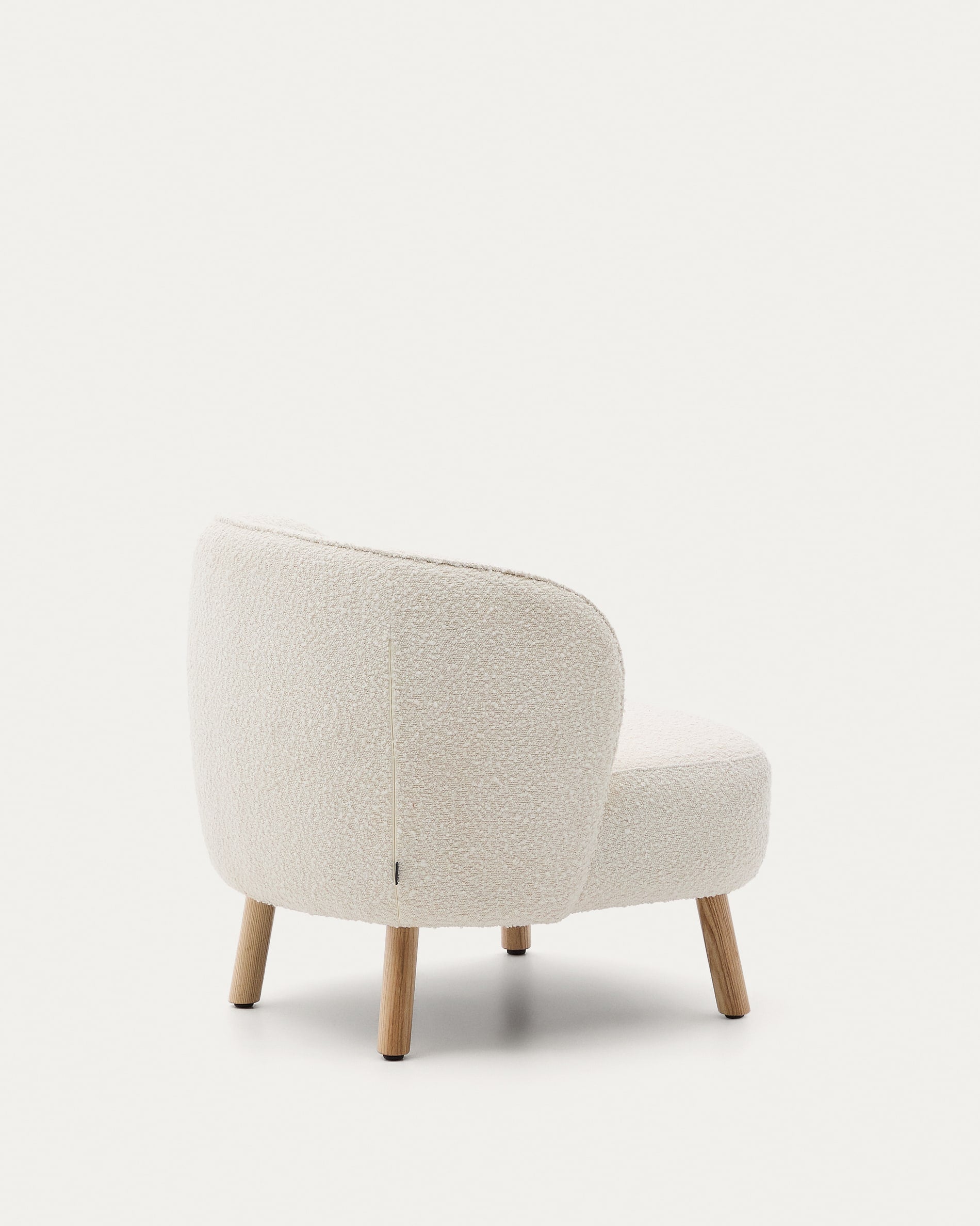 Eleganter Sessel mit weissem Schaffellbezug und stabilen Buchenholzbeinen, ideal für stilvolle, kompakte Räume.