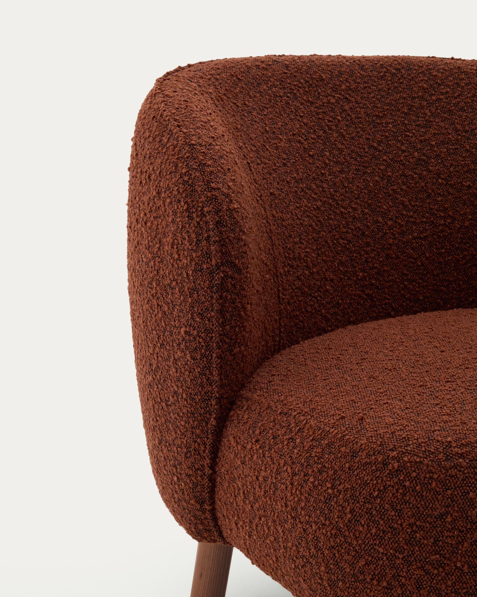 Stylischer Sessel Ulit in terrakottafarbenem Lammfellimitat, ausgestattet mit robusten Eschenholzbeinen in edlem Nussbaum-Finish.
