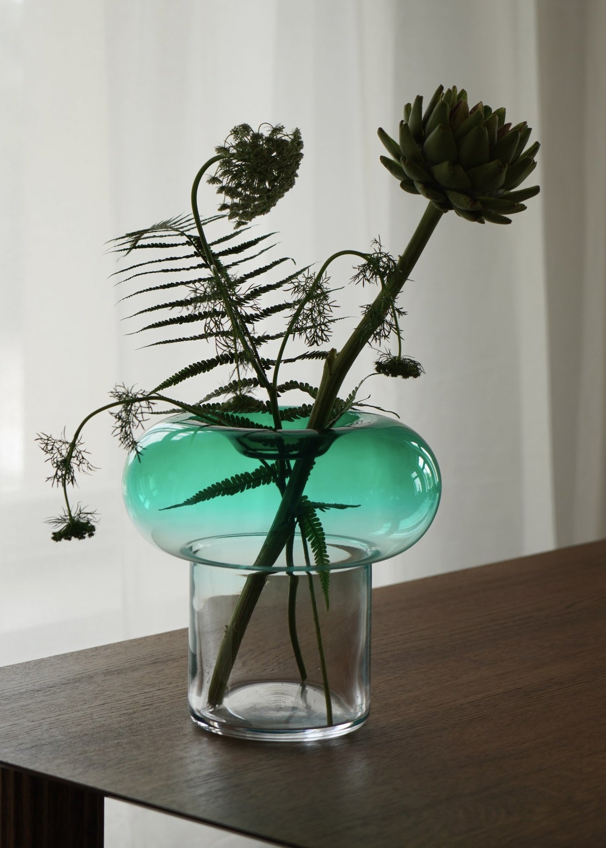 Bernsteinfarbene Glasvase Orio von Tamo mit runder, skulpturaler Form aus mundgeblasenem, handbemaltem Glas auf hellem Hintergrund.