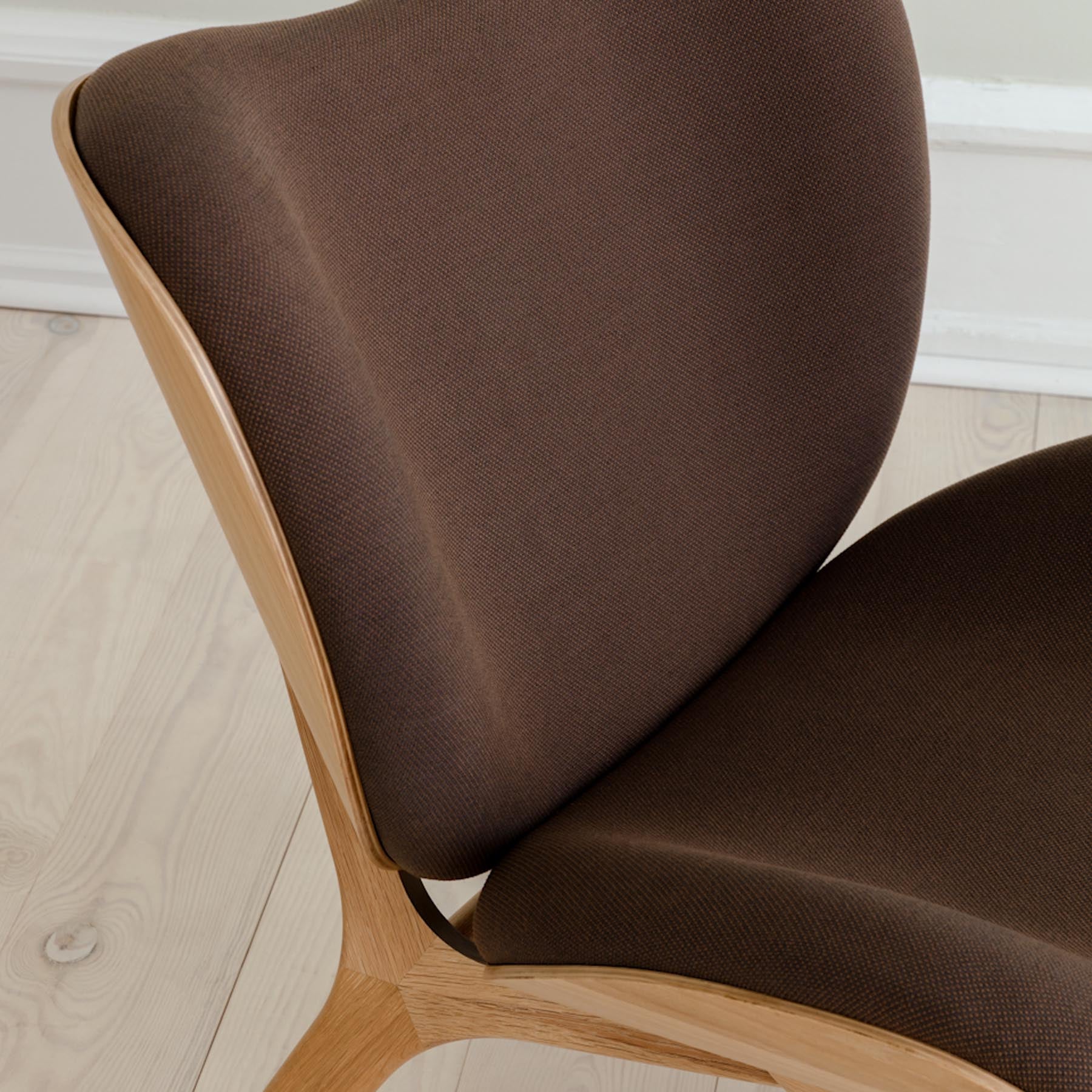 Moderner A Conversation Piece Low Sessel in Mocca, perfekt für gemütliche Ecken, umgeben von stilvollem Interieur und warmem Licht.