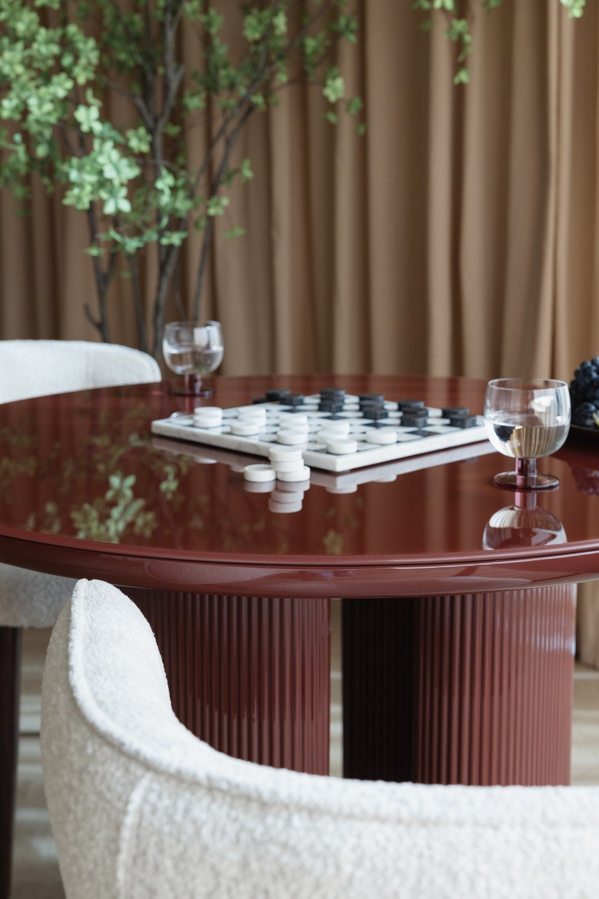 Runder Esstisch Dining Table Timo mit roter Hochglanz-Tischplatte und schwarzem Gestell aus Eisen mit vier gerillten Beinen in der Mitte.