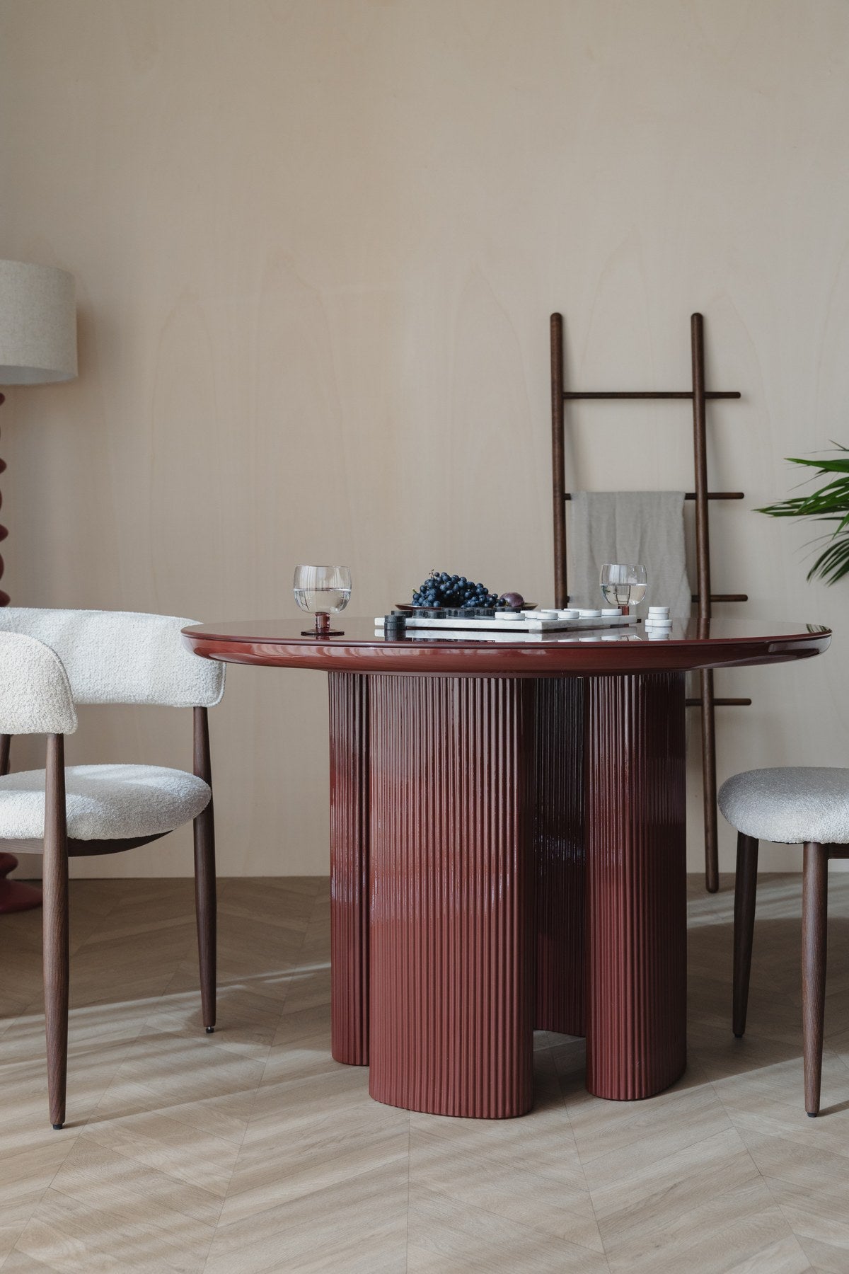 Runder Esstisch Dining Table Timo mit roter Hochglanz-Tischplatte und schwarzem Gestell aus Eisen mit vier gerillten Beinen in der Mitte.