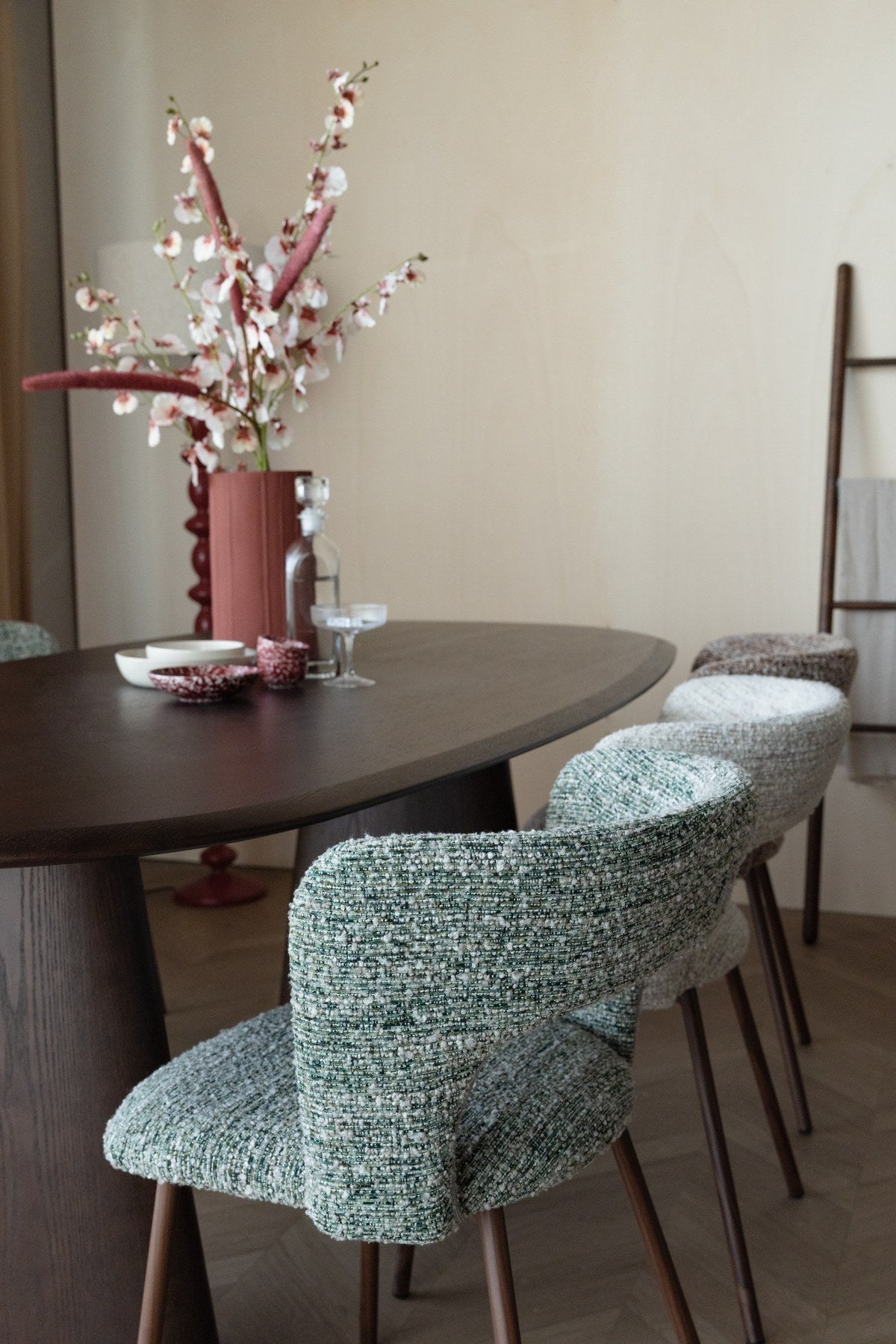 Stuhl Chelsea von White Label Living mit beigem, grob gewebtem Polsterbezug und schlankem Gestell mit bogenförmiger Rückenlehne.