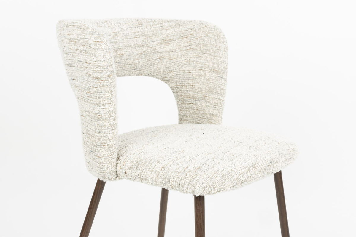 Stuhl Chelsea von White Label Living mit beigem, grob gewebtem Polsterbezug und schlankem Gestell mit bogenförmiger Rückenlehne.