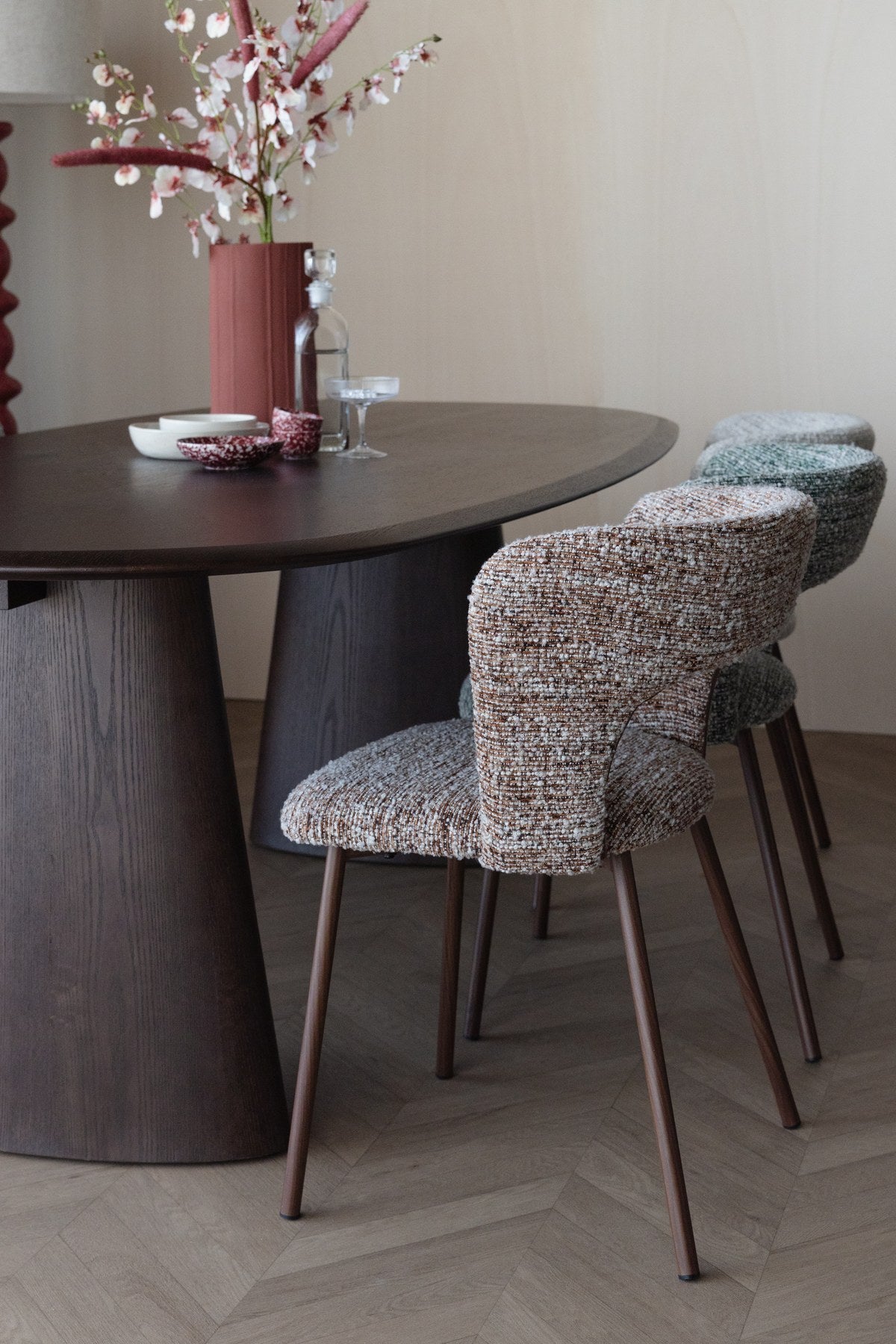 Stuhl Chelsea von White Label Living mit beigem, grob gewebtem Polsterbezug und schlankem Gestell mit bogenförmiger Rückenlehne.