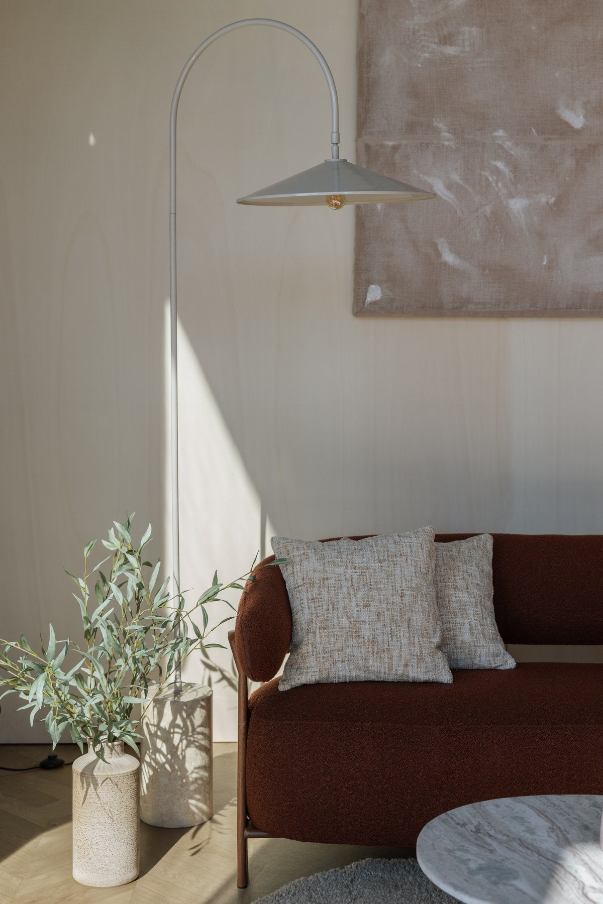 Stehleuchte Enno von White Label Living: grauer Metallschirm, gebogener Metallarm und zylindrischer Travertin-Fuss in schlankem Design.