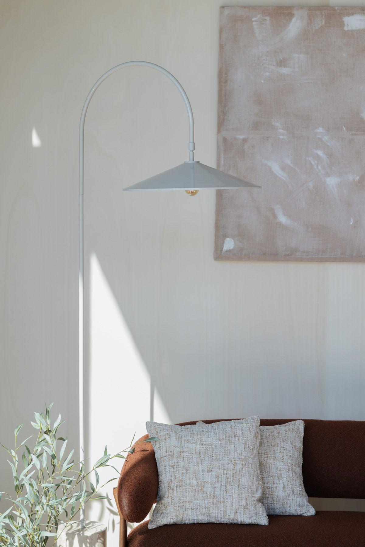Stehleuchte Enno von White Label Living: grauer Metallschirm, gebogener Metallarm und zylindrischer Travertin-Fuss in schlankem Design.