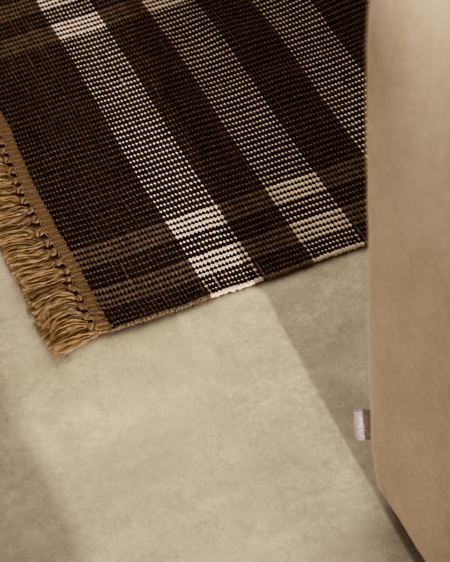 Erleben Sie den eleganten Teppich Barani (60 x 90 cm) von Kave Home – ein handgefertigtes Unikat aus robusten Synthetikfasern in Braun und Schwarz.