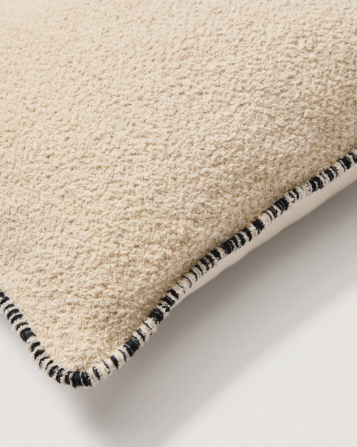 Quadratischer Kissenbezug aus Baumwoll-Bouclé in Beige mit schwarzer Kontrastpaspel und Reissverschluss, Grösse 50 x 50 cm.